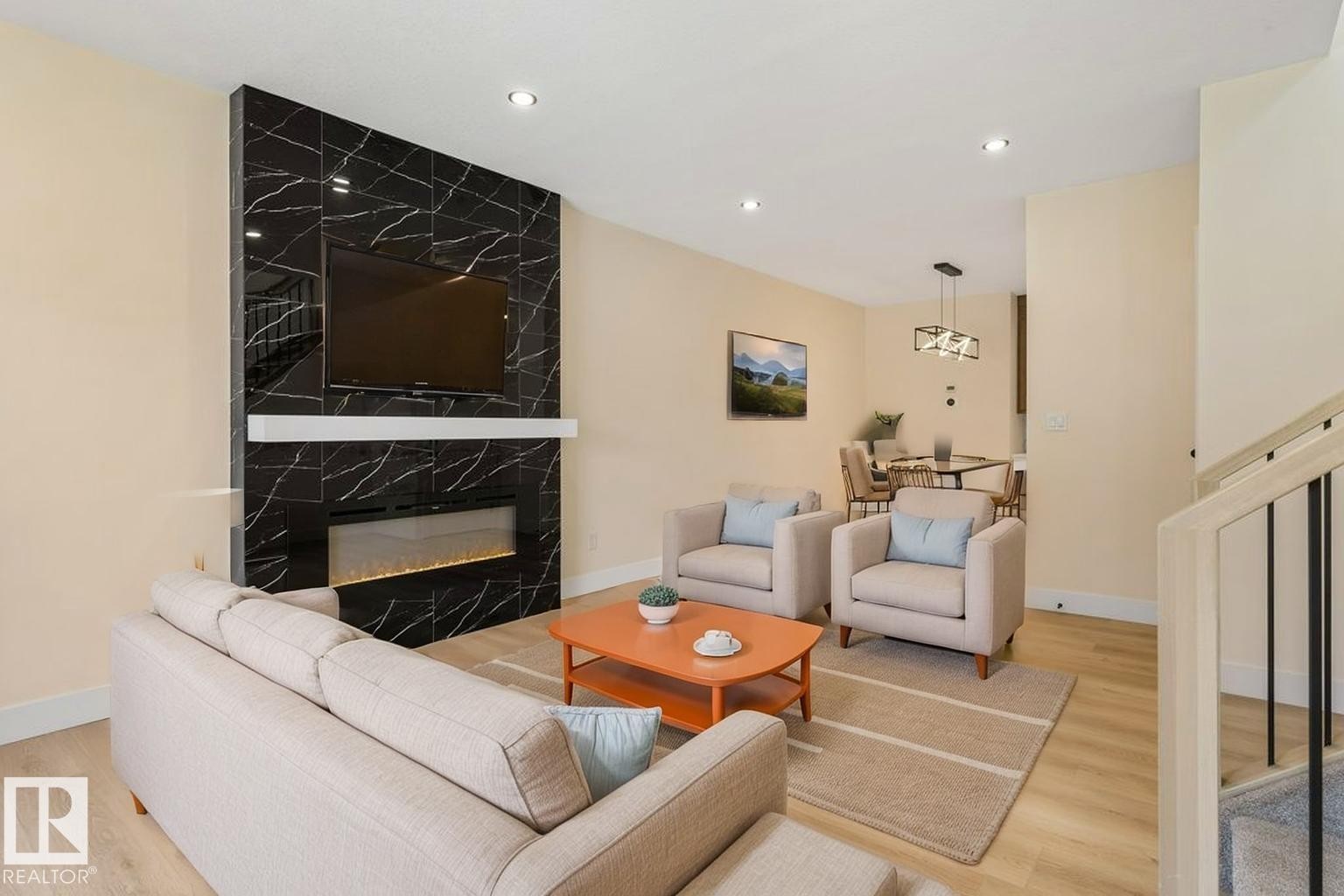 Living area featuring a black marble-patterned accent wall with an integrated electric fireplace and a wall-mounted television - 10323 79 Street Nw, Edmonton, AB - Indoor Photo Showing Living Room With Fireplace
