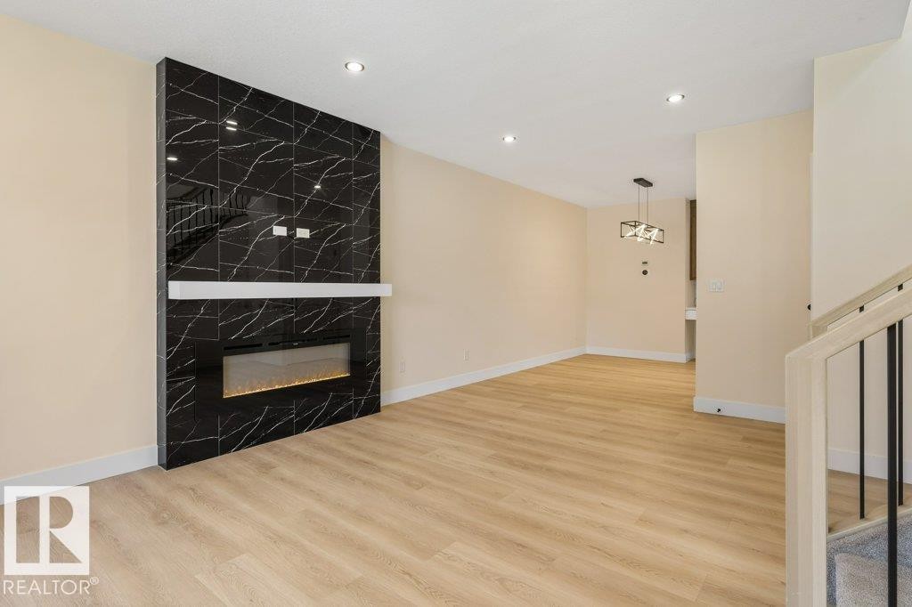 Statement fireplace featuring black tile with white veining and an electric insert - 10323 79 Street Nw, Edmonton, AB - Indoor With Fireplace