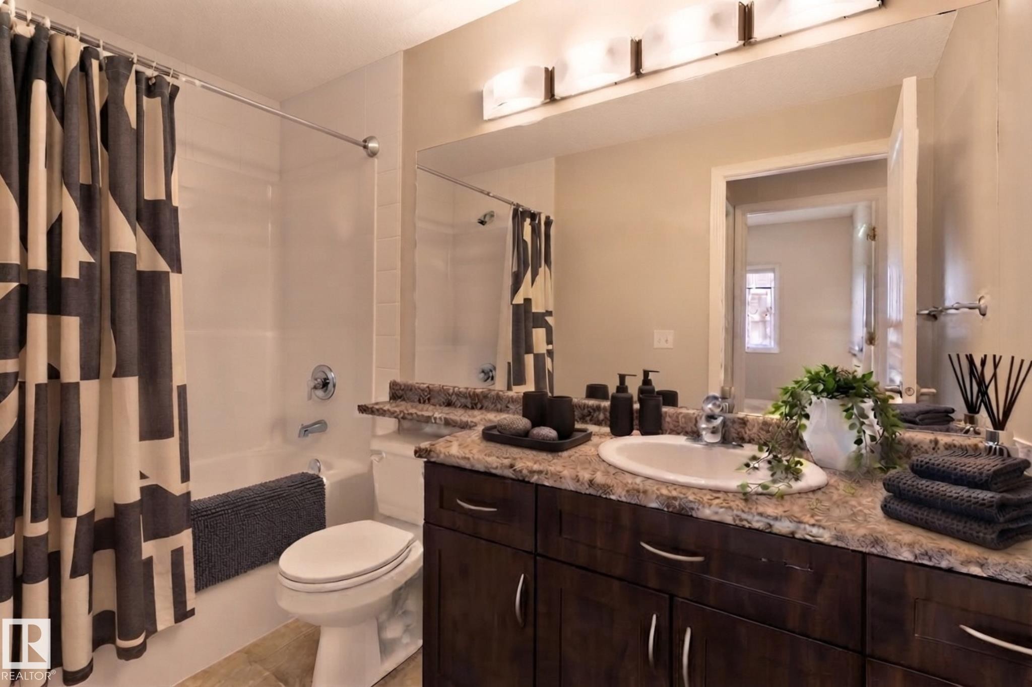 Brown wood-finish vanity with a built-in sink, stone-finish countertop, and wall-mounted mirror - #120 8931 156 St Nw, Edmonton, AB