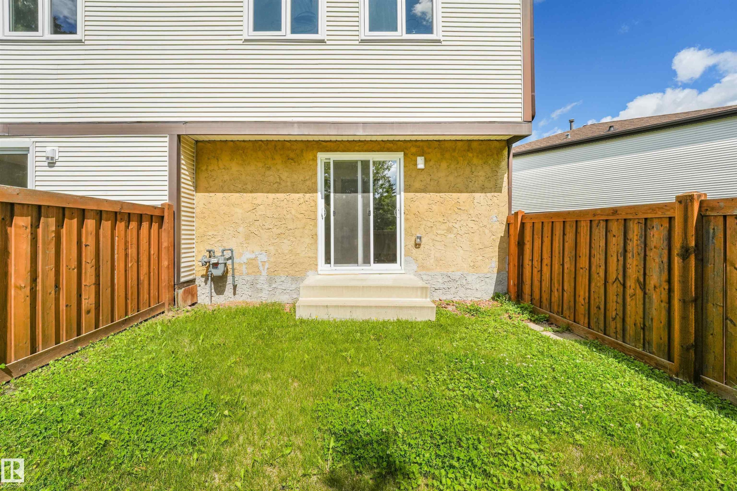 Sliding glass patio door with concrete steps opening onto a private fenced yard with grass - #39 14511 52 Street Nw, Edmonton, AB - Outdoor With Exterior