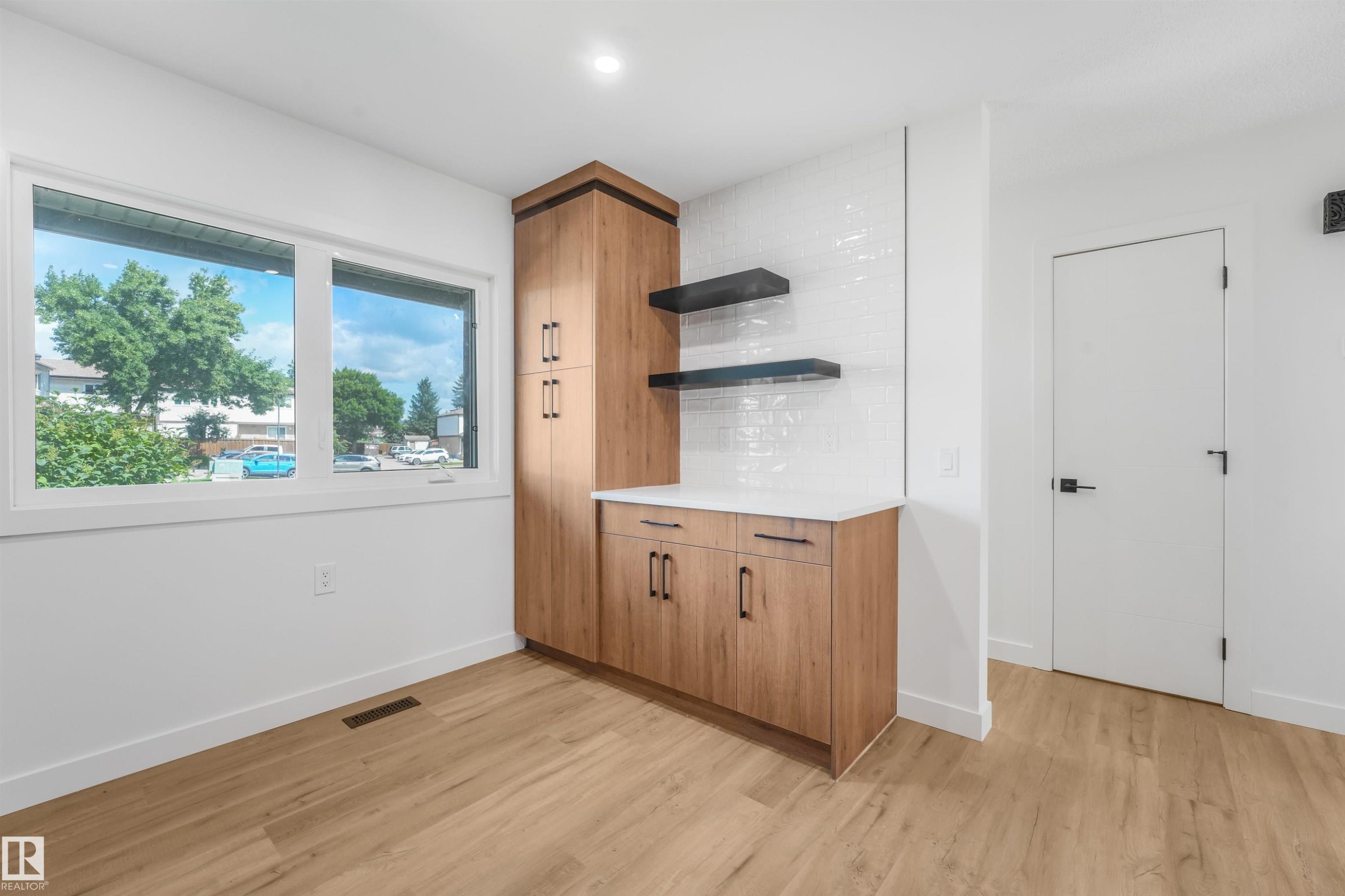 Light wood-finish flooring complements a built-in wood-finish cabinetry unit with a solid surface countertop - #39 14511 52 Street Nw, Edmonton, AB - Indoor Photo Showing Other Room