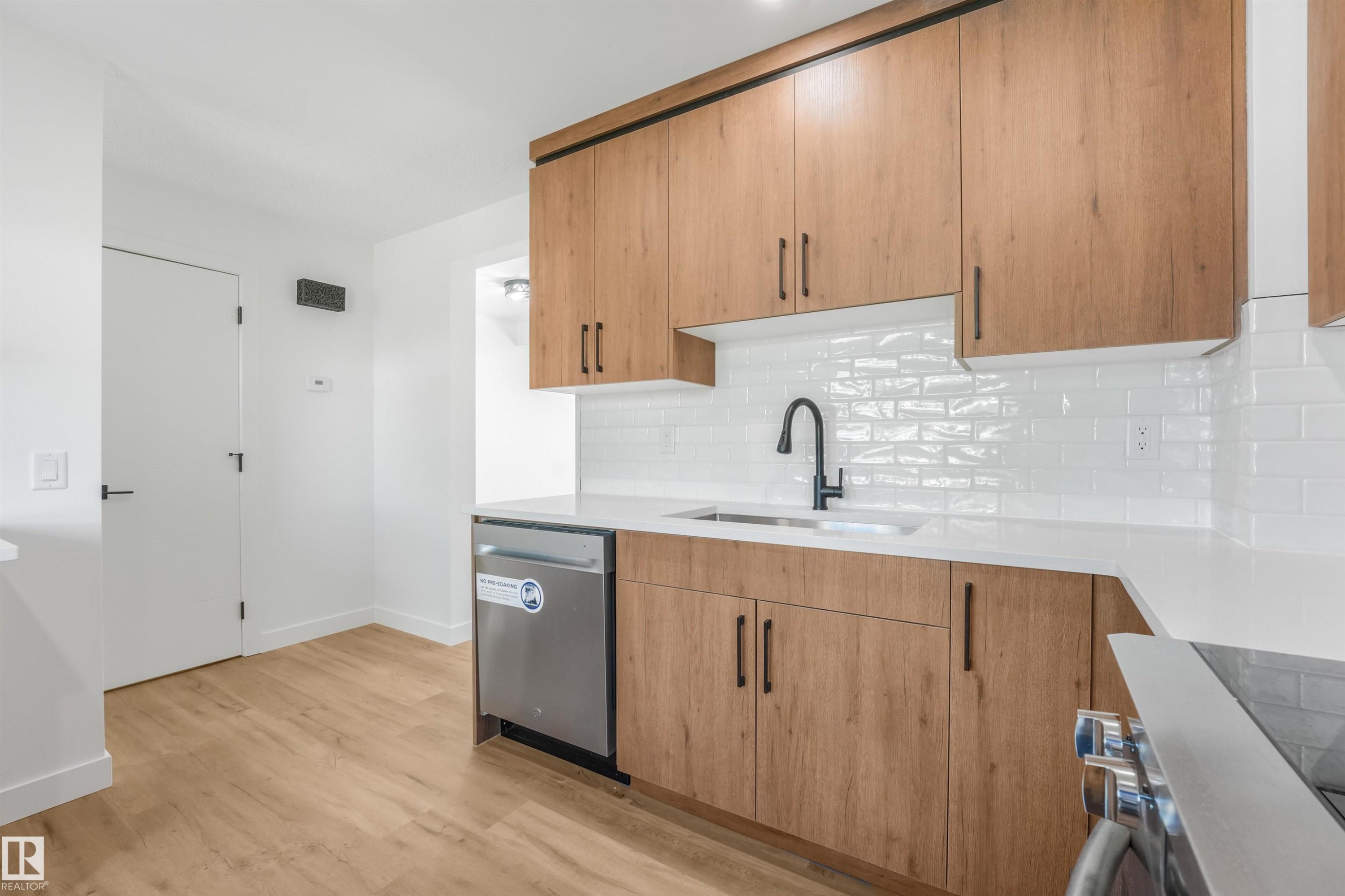 Contemporary kitchen featuring wood-finish cabinetry, white subway tile backsplash, and light-toned countertops - #39 14511 52 Street Nw, Edmonton, AB - Indoor Photo Showing Kitchen