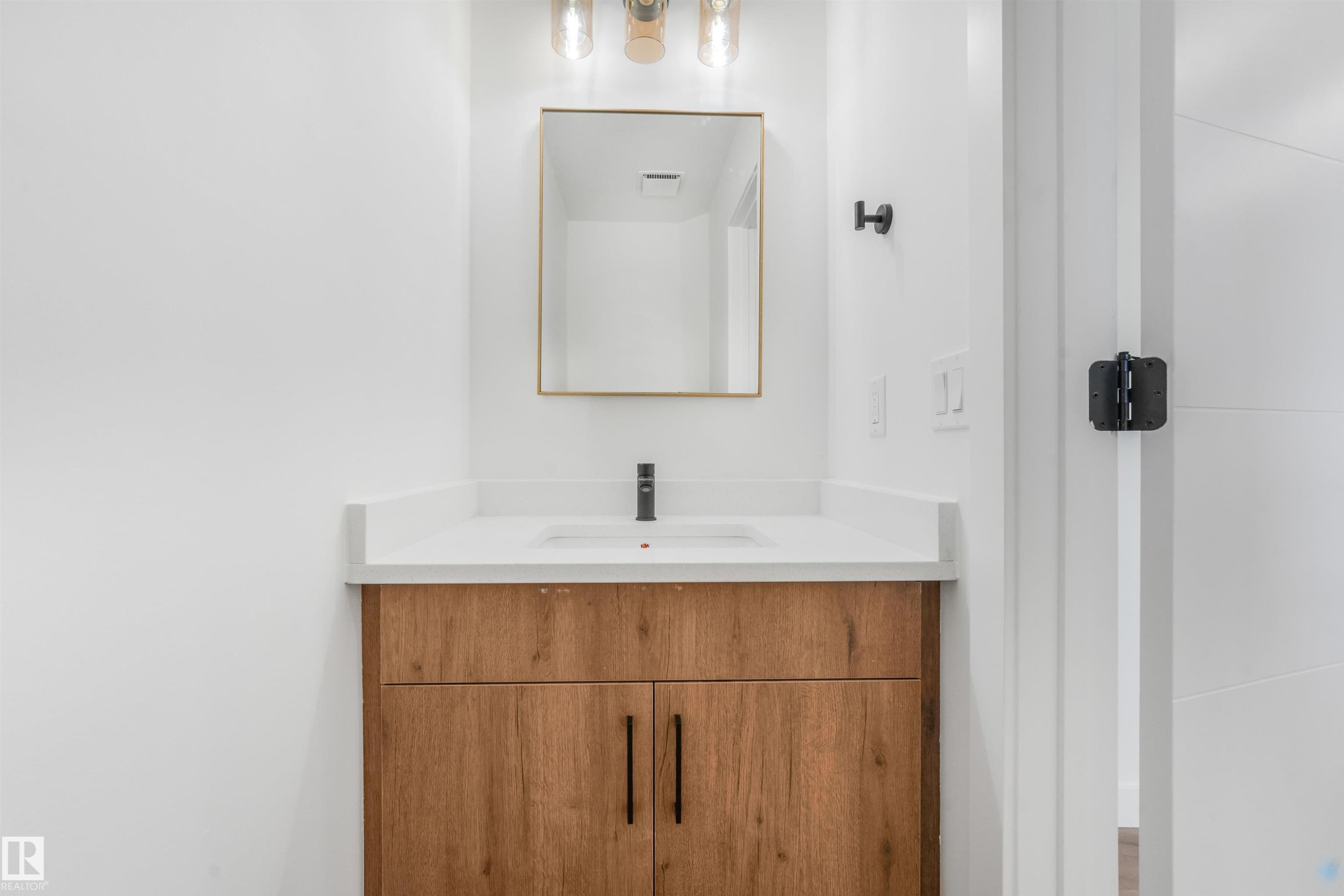Modern vanity featuring a wood-finish cabinet, white countertop, and integrated sink - #39 14511 52 Street Nw, Edmonton, AB - Indoor Photo Showing Bathroom
