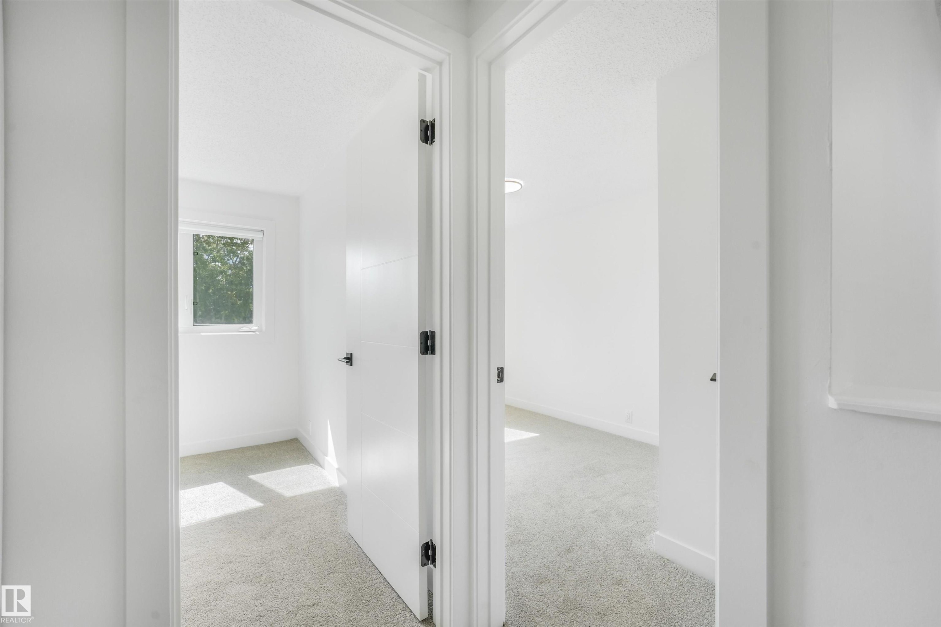 Hallway with light gray carpeting and white walls, leading to two rooms - #39 14511 52 Street Nw, Edmonton, AB - Indoor Photo Showing Other Room