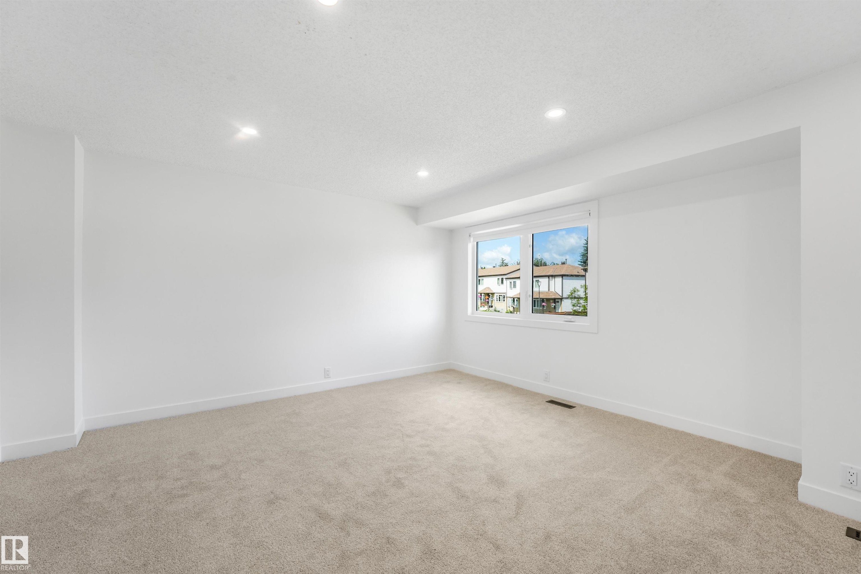 Bright interior space featuring a double-paned window, recessed lighting, neutral carpeting, white baseboards, and a white ceiling - #39 14511 52 Street Nw, Edmonton, AB - Indoor Photo Showing Other Room