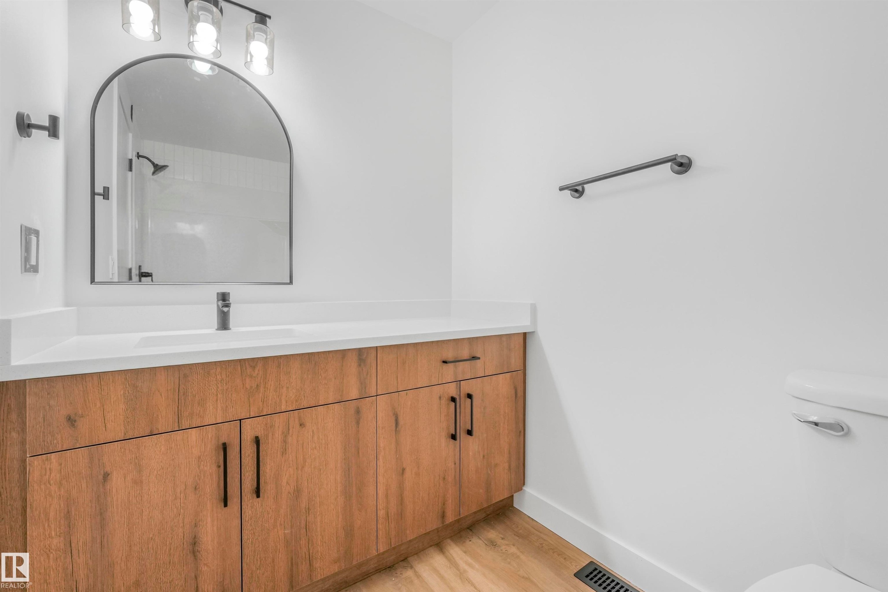 Vanity featuring a white countertop with integrated sink, wood-finish cabinetry, and matte black hardware - #39 14511 52 Street Nw, Edmonton, AB - Indoor Photo Showing Bathroom