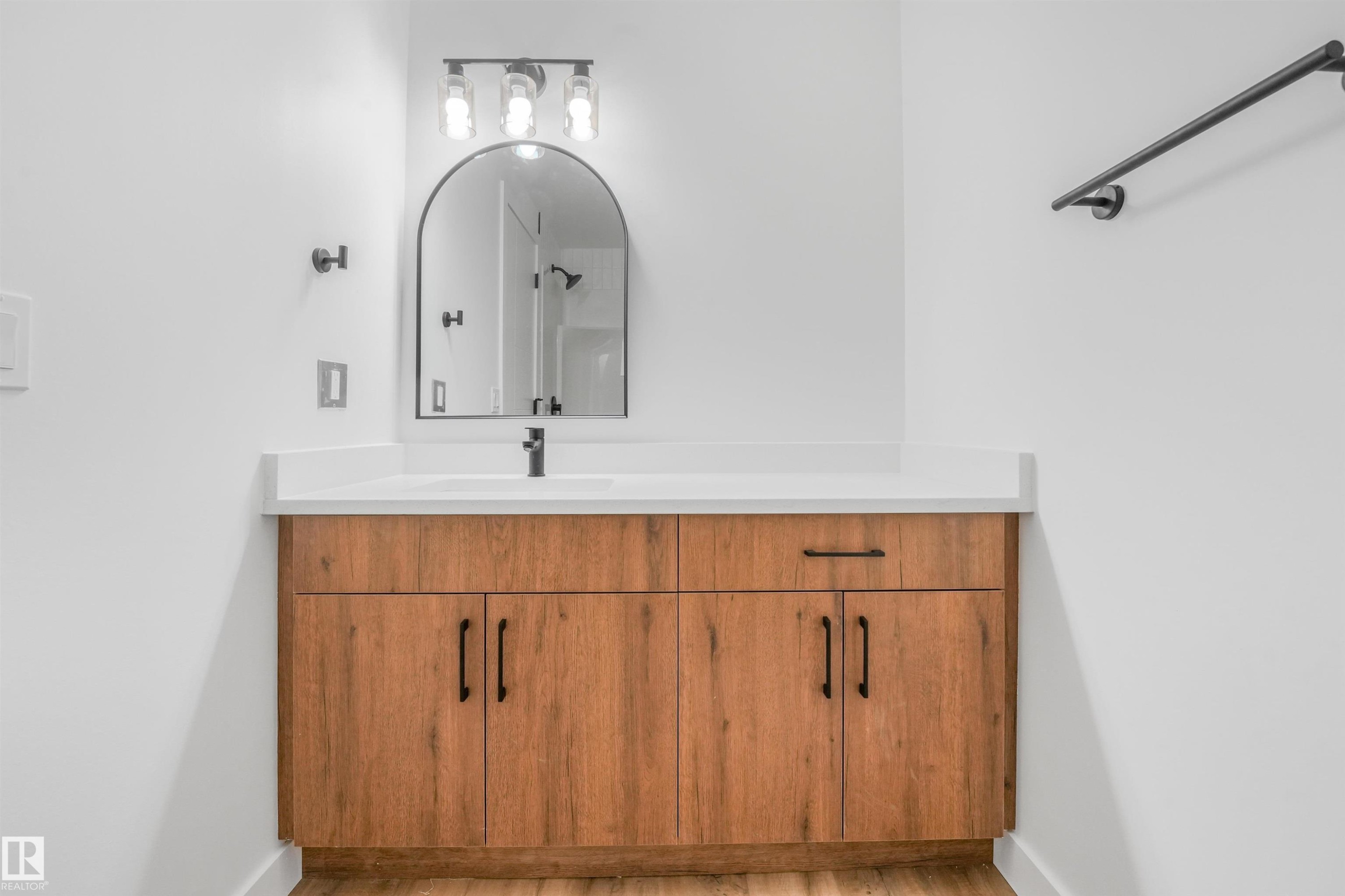 Bathroom vanity featuring a wood-finish cabinet, white countertop, and integrated sink - #39 14511 52 Street Nw, Edmonton, AB - Indoor