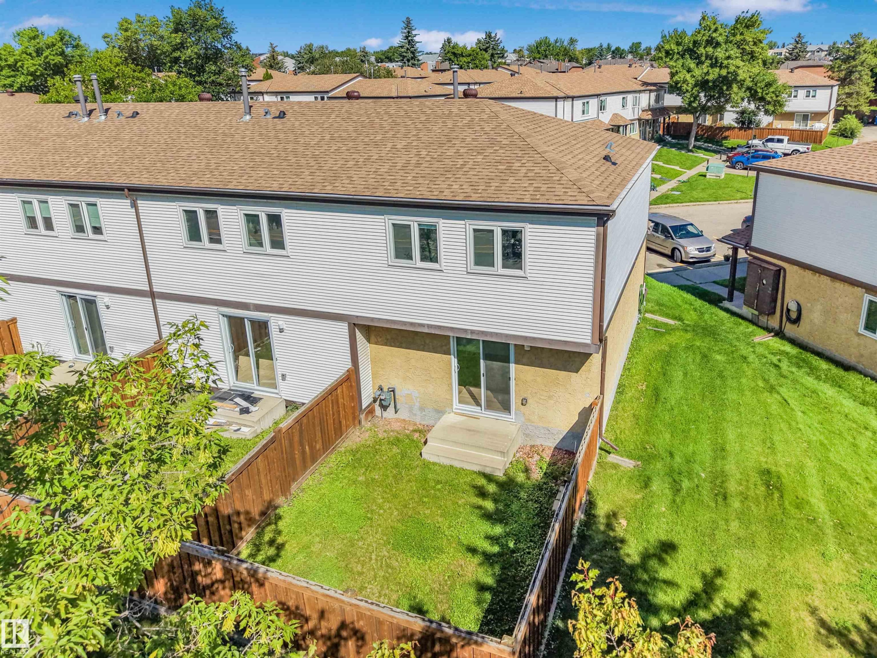 Townhome exterior featuring white siding and a brown shingle roof - #39 14511 52 Street Nw, Edmonton, AB - Outdoor