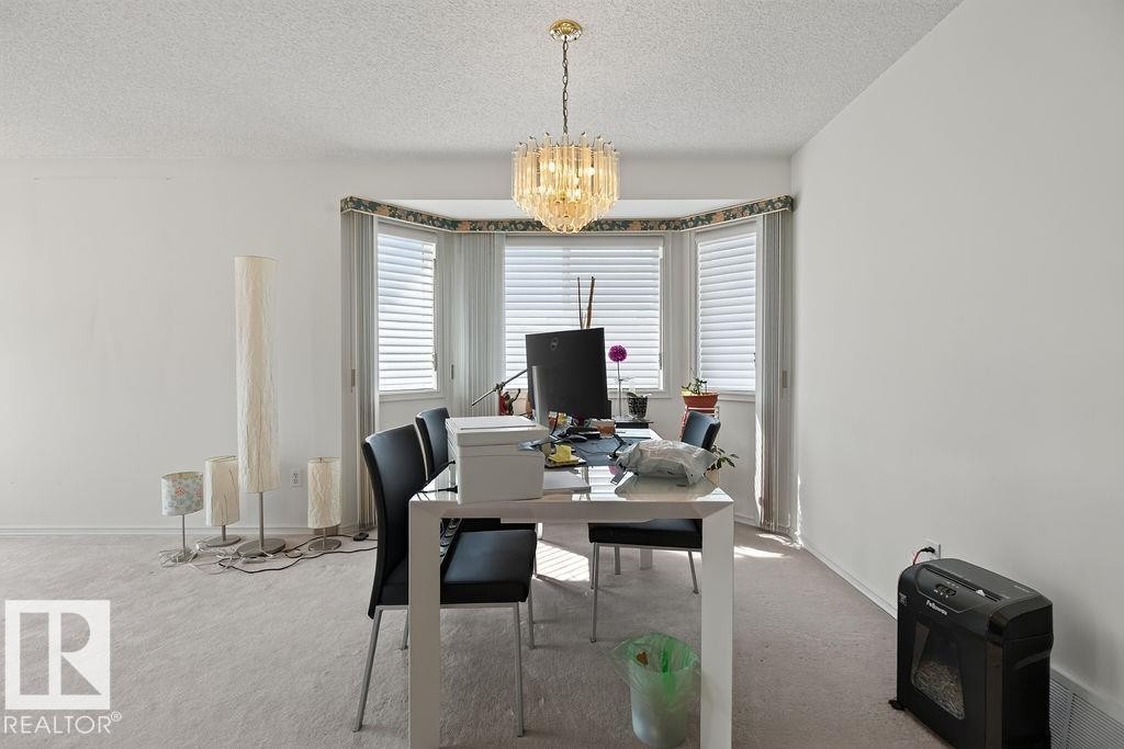 Recessed bay window with multiple vertical blinds, complemented by a gold-toned chandelier - 1046 Jones Crescent Nw, Edmonton, AB - Indoor Photo Showing Dining Room