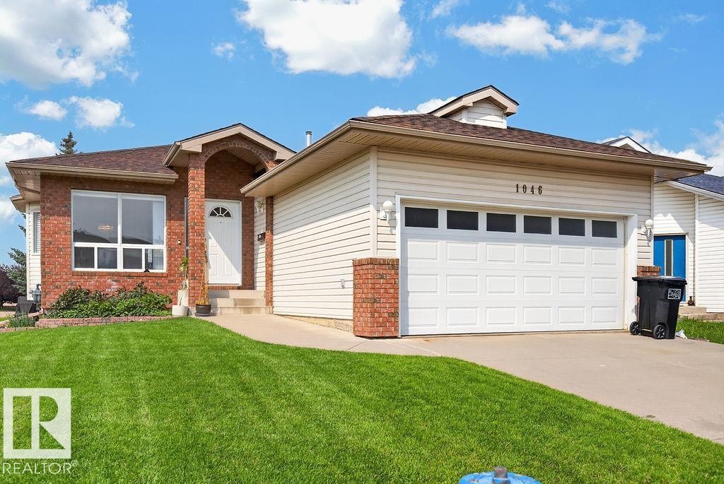 Exterior featuring a brick and siding facade, a two-car garage with transom windows, a concrete driveway, a front entry with an arched portico, and a landscaped lawn - 1046 Jones Crescent Nw, Edmonton, AB - Outdoor