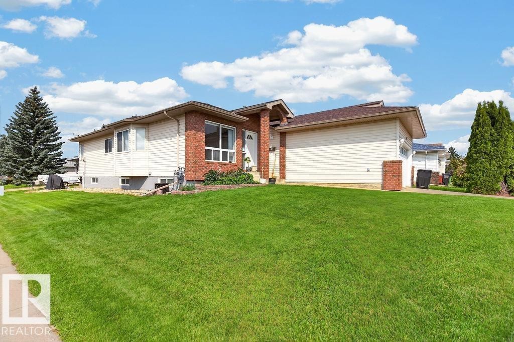 Exterior featuring brick and siding finishes, an attached garage, a mature conifer, and a front lawn - 1046 Jones Crescent Nw, Edmonton, AB - Outdoor