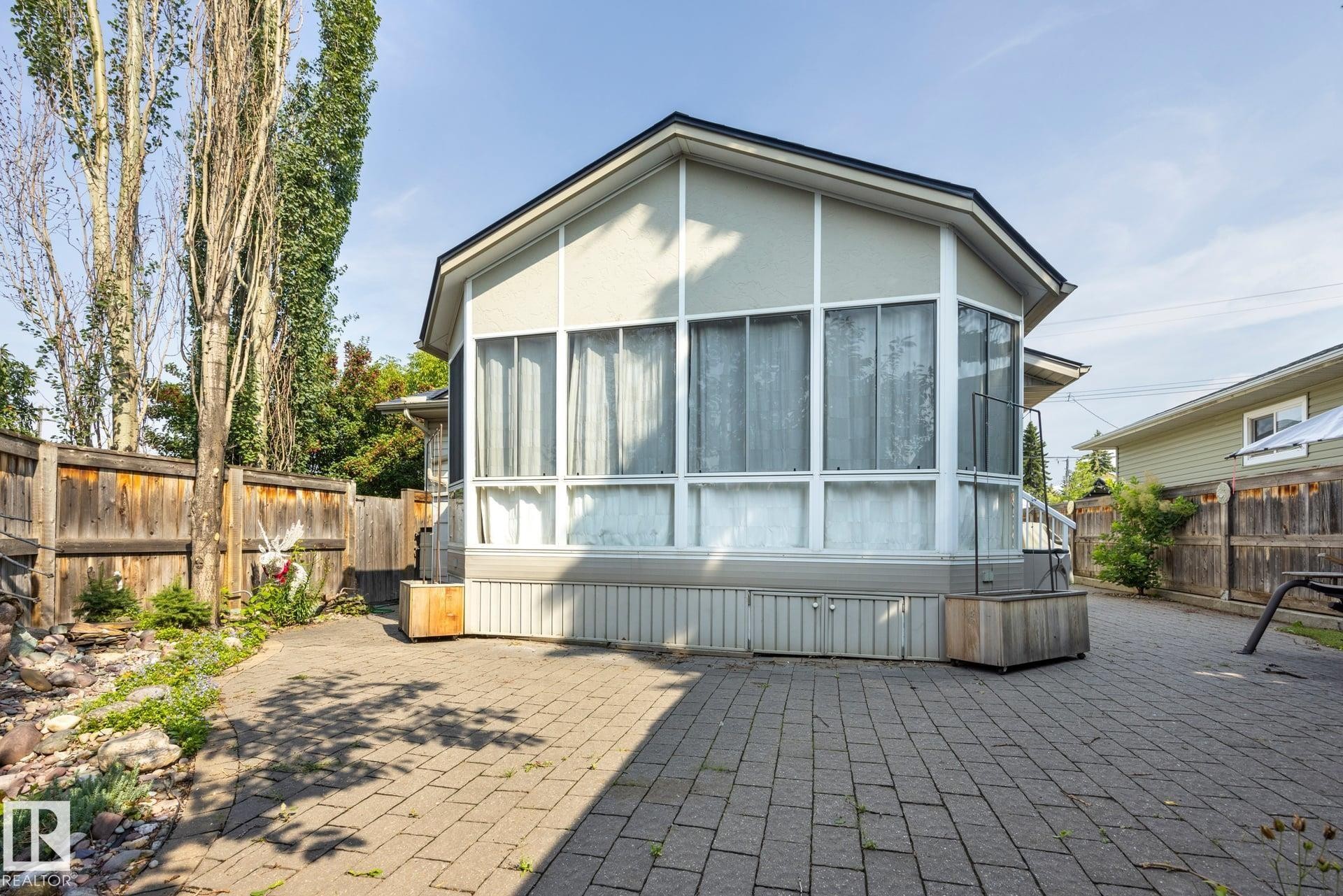 Modern residential structure featuring expansive multi-panel windows, peaked roofline with contemporary architectural detailing, and corrugated metal siding accents - 9503 54 Street Nw, Edmonton, AB