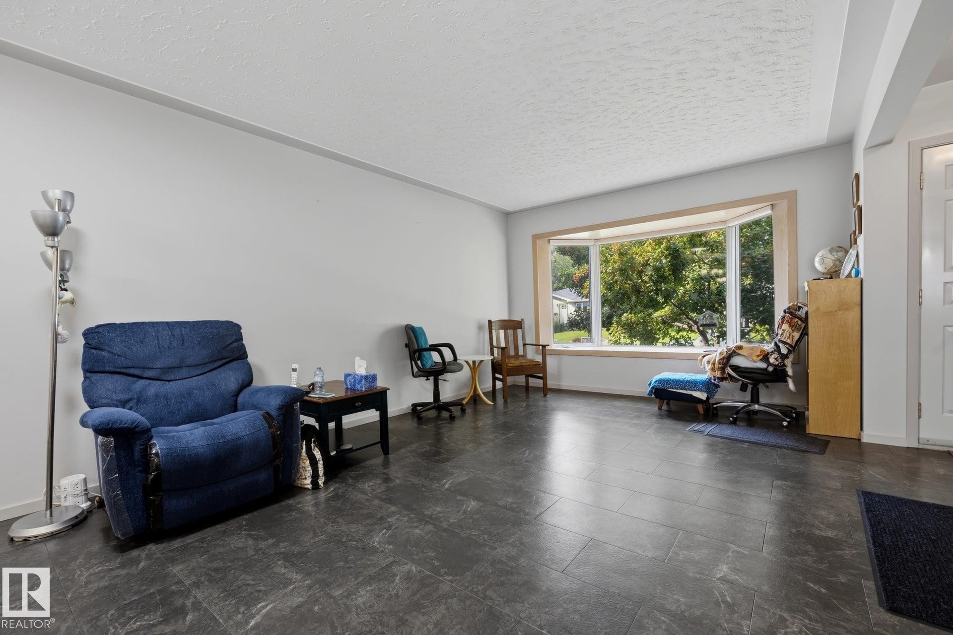 Spacious open-concept living area featuring polished concrete flooring, expansive multi-pane windows with natural light, and generous square footage - 9503 54 Street Nw, Edmonton, AB