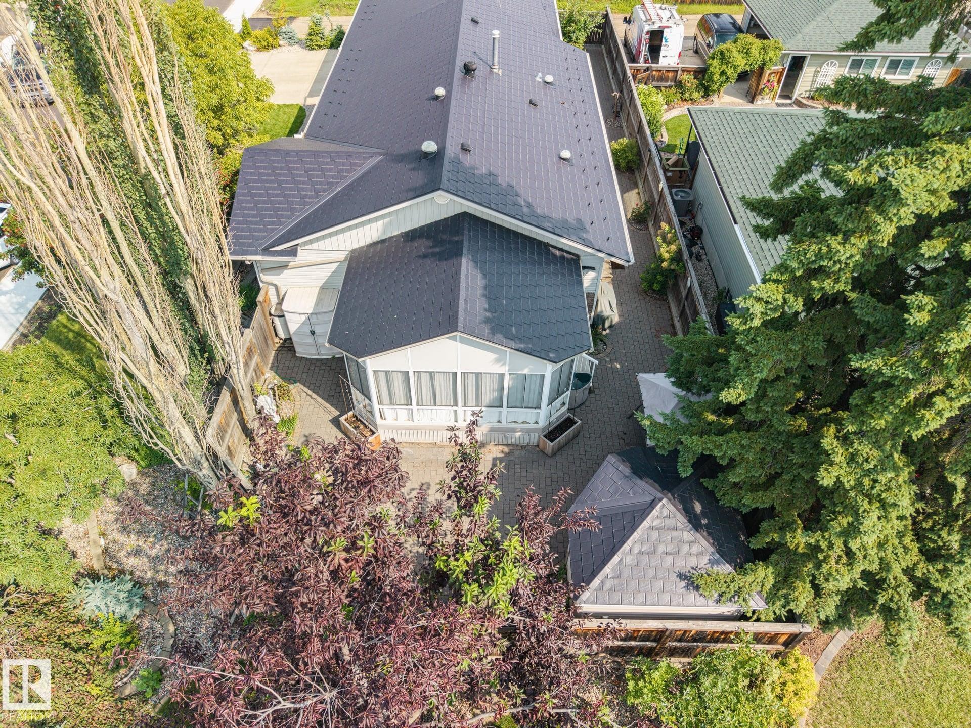 Patio area featuring paver stone hardscaping, mature trees, and an enclosed sunroom - 9503 54 Street Nw, Edmonton, AB