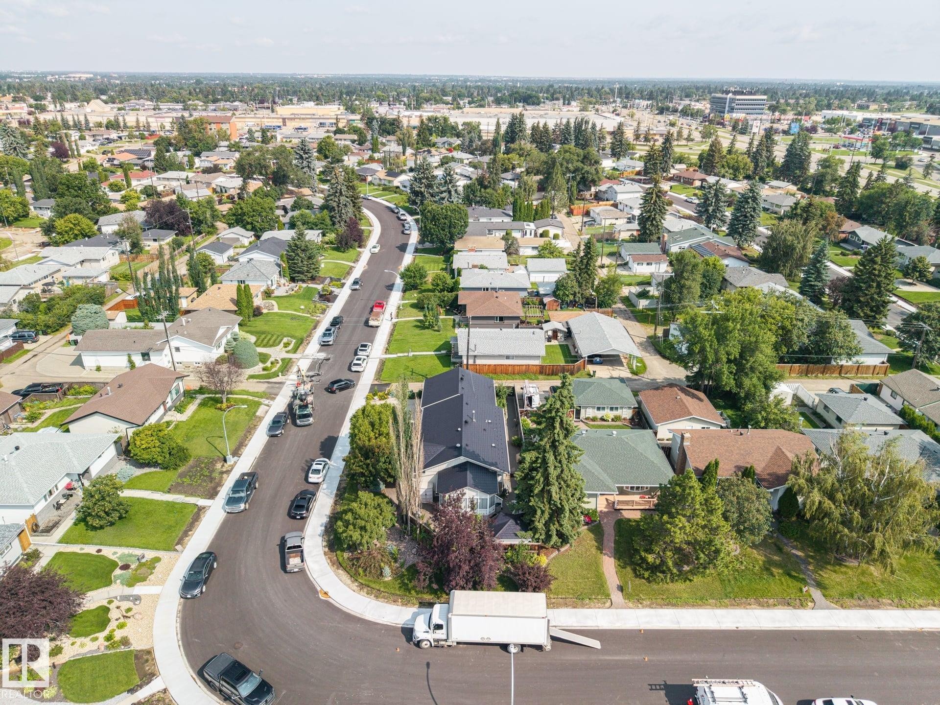 Aerial view showcasing a well-landscaped residential property featuring mature trees, manicured lawn, and a curved driveway with ample parking - 9503 54 Street Nw, Edmonton, AB