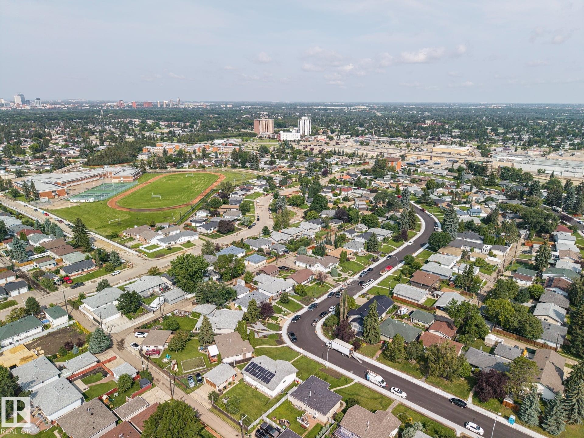 Aerial perspective of a residential neighborhood with a curved street layout, mature trees, and a sports field - 9503 54 Street Nw, Edmonton, AB