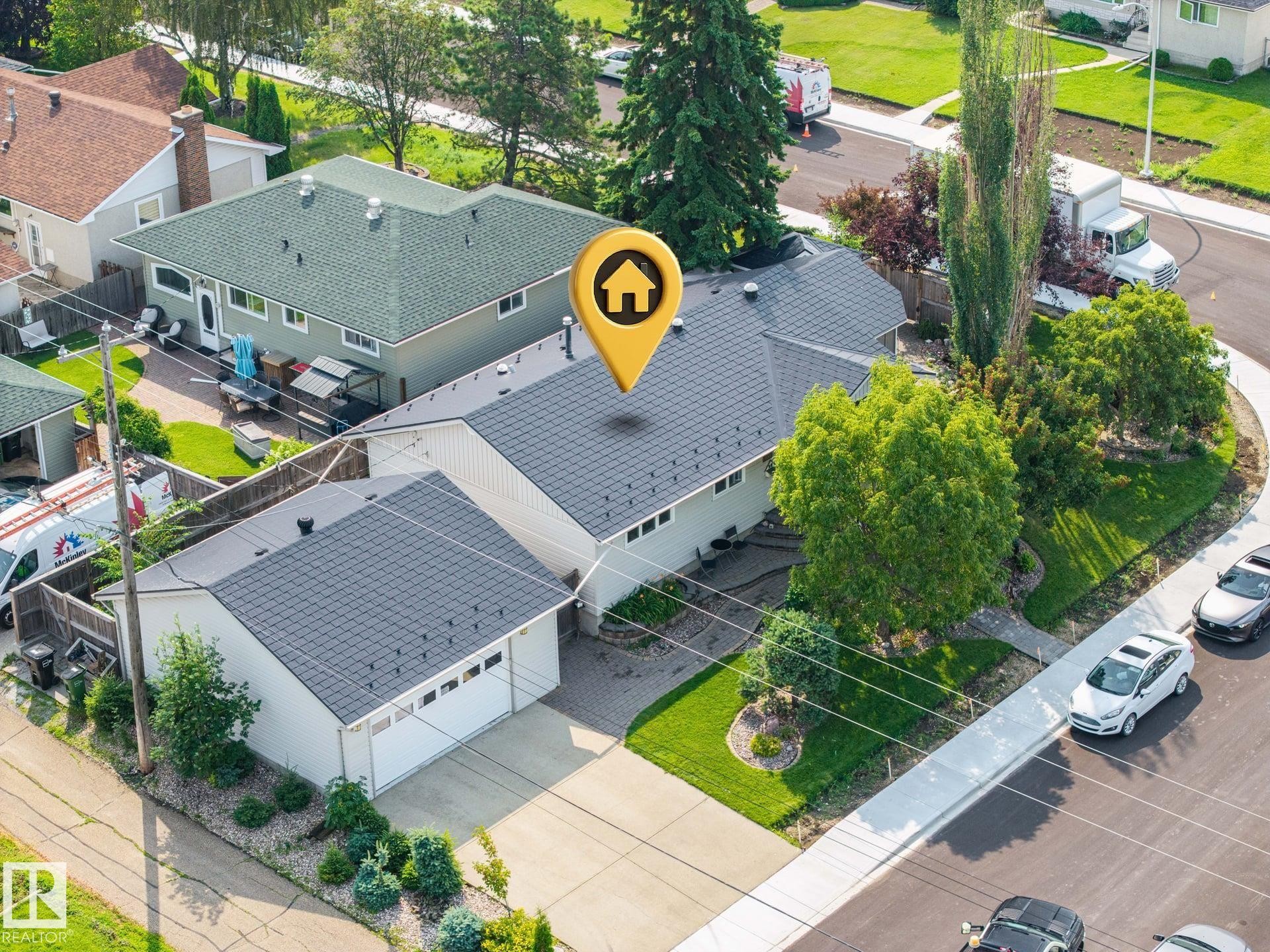 Charming single-story residence featuring a freshly resurfaced dark gray asphalt shingle roof, detached two-car garage with matching roofline, and mature landscaping including tall evergreen trees and manicured lawn - 9503 54 Street Nw, Edmonton, AB