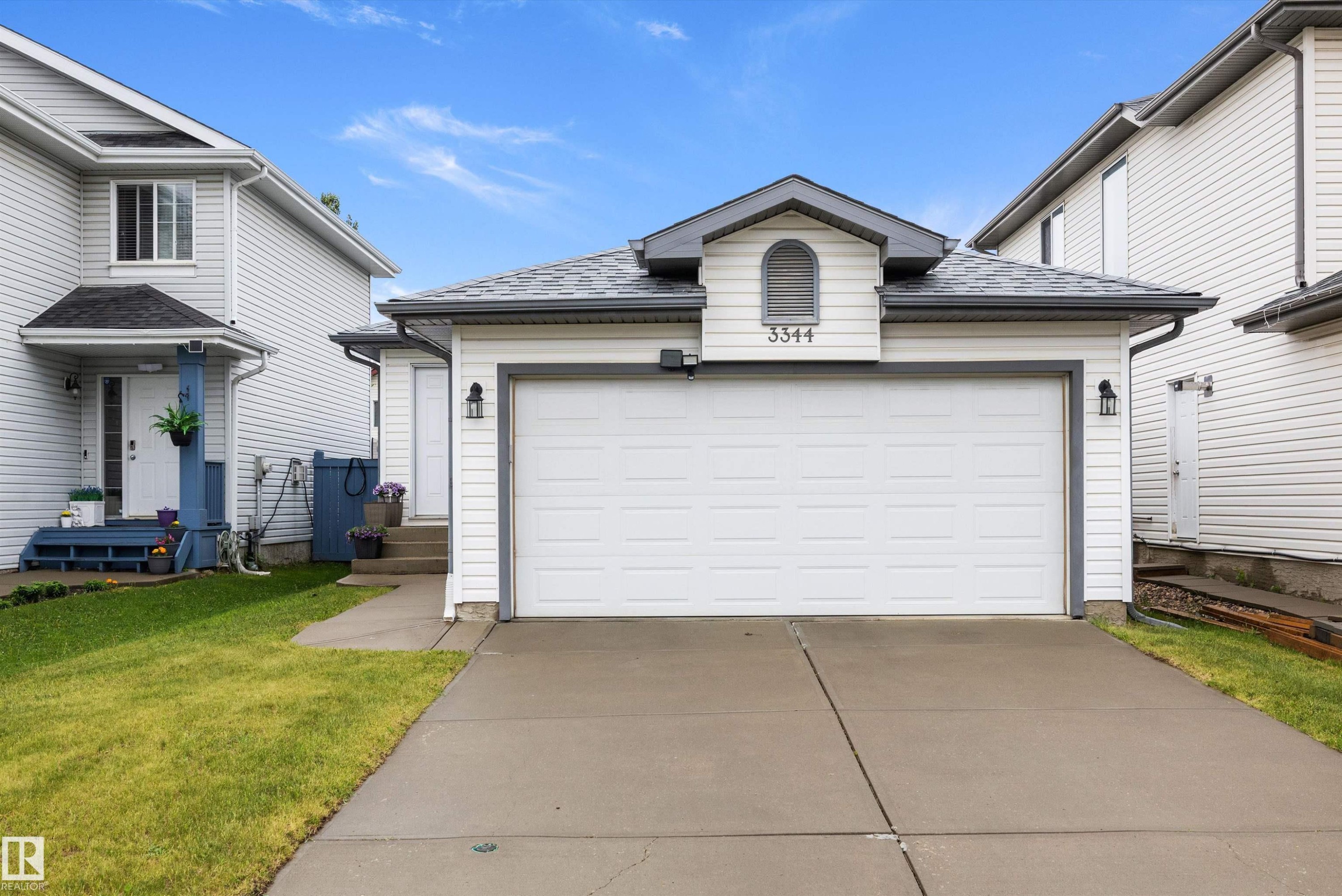 Two-story residence featuring white siding and a prominent two-car garage - 3344 24 Avenue Nw, Edmonton, AB - Outdoor With Exterior