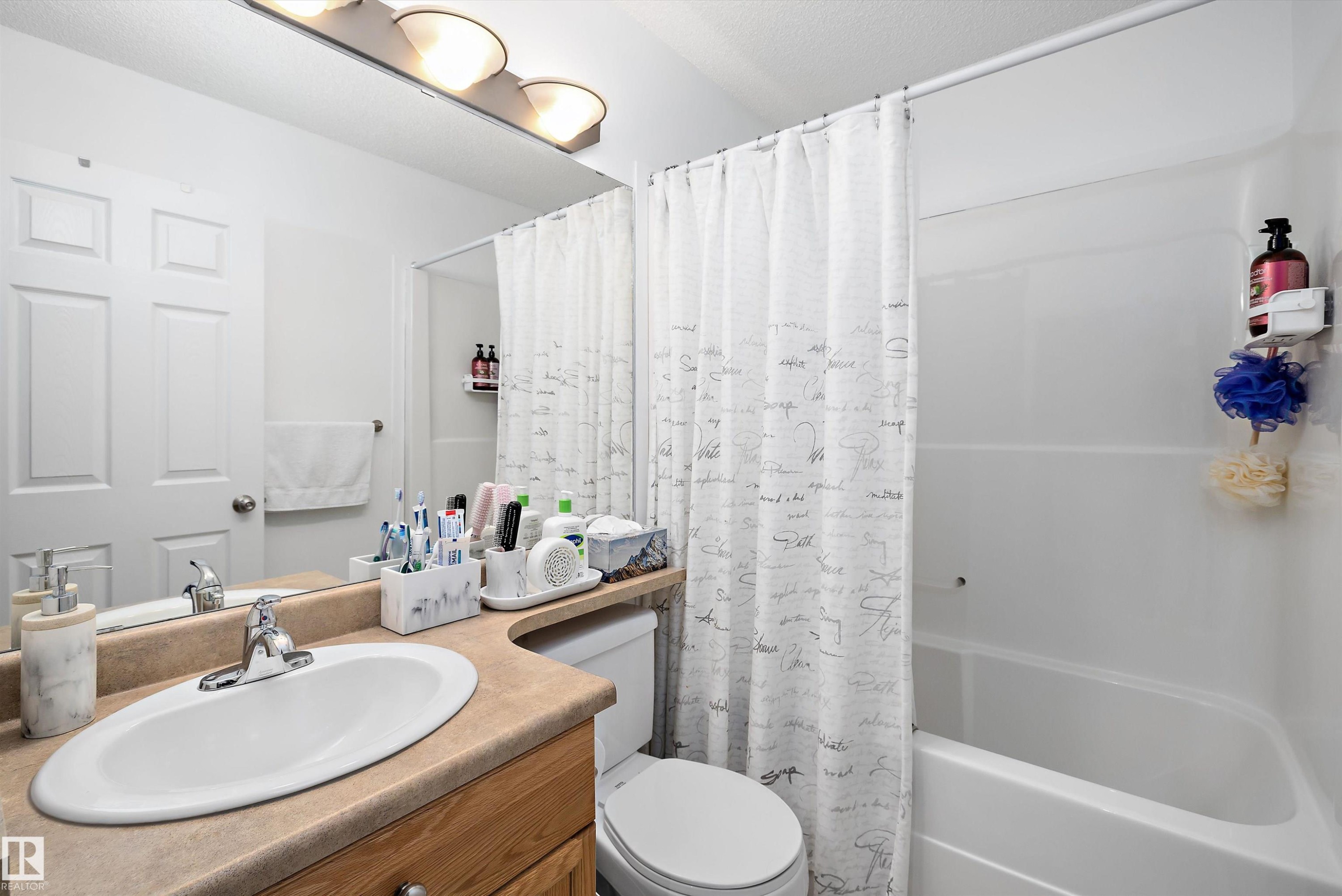 Bathroom featuring a single vanity with an integrated sink, a wood-finish cabinet, and a beige countertop - 3344 24 Avenue Nw, Edmonton, AB - Indoor Photo Showing Bathroom