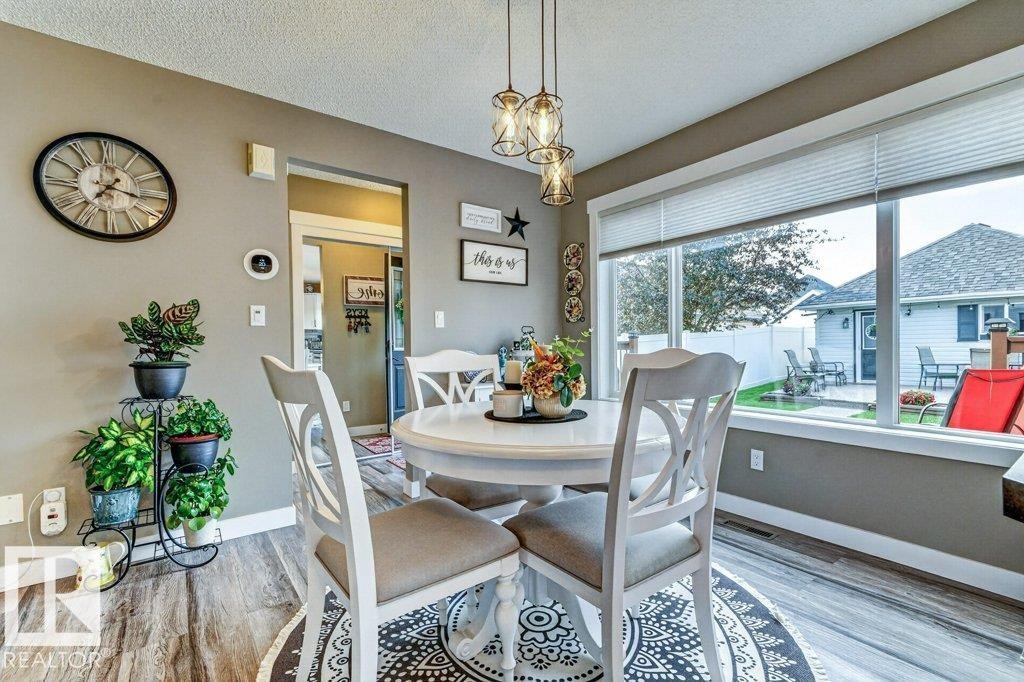 Dining area featuring wood-finish flooring and a contemporary multi-light pendant fixture - 5322 Terwillegar Boulevard Nw, Edmonton, AB - Indoor Photo Showing Dining Room