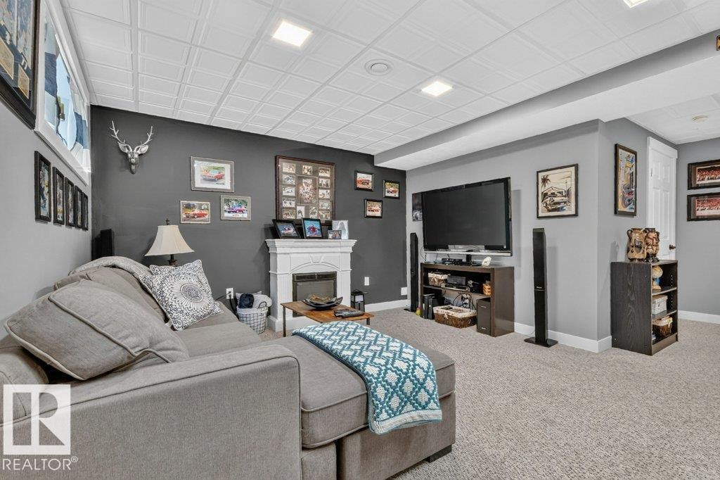 Finished lower level featuring recessed lighting, a decorative fireplace surround, neutral wall paint, and light-colored carpeting - 5322 Terwillegar Boulevard Nw, Edmonton, AB - Indoor With Fireplace