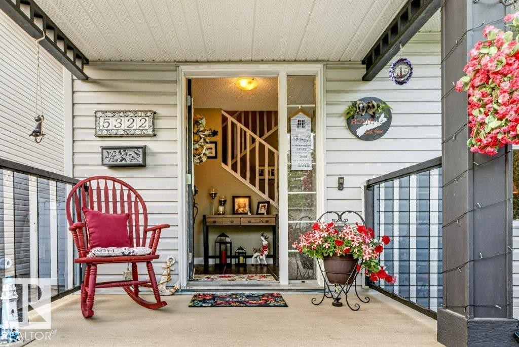 Covered front porch featuring light-colored siding, dark trim, and a concrete floor - 5322 Terwillegar Boulevard Nw, Edmonton, AB -