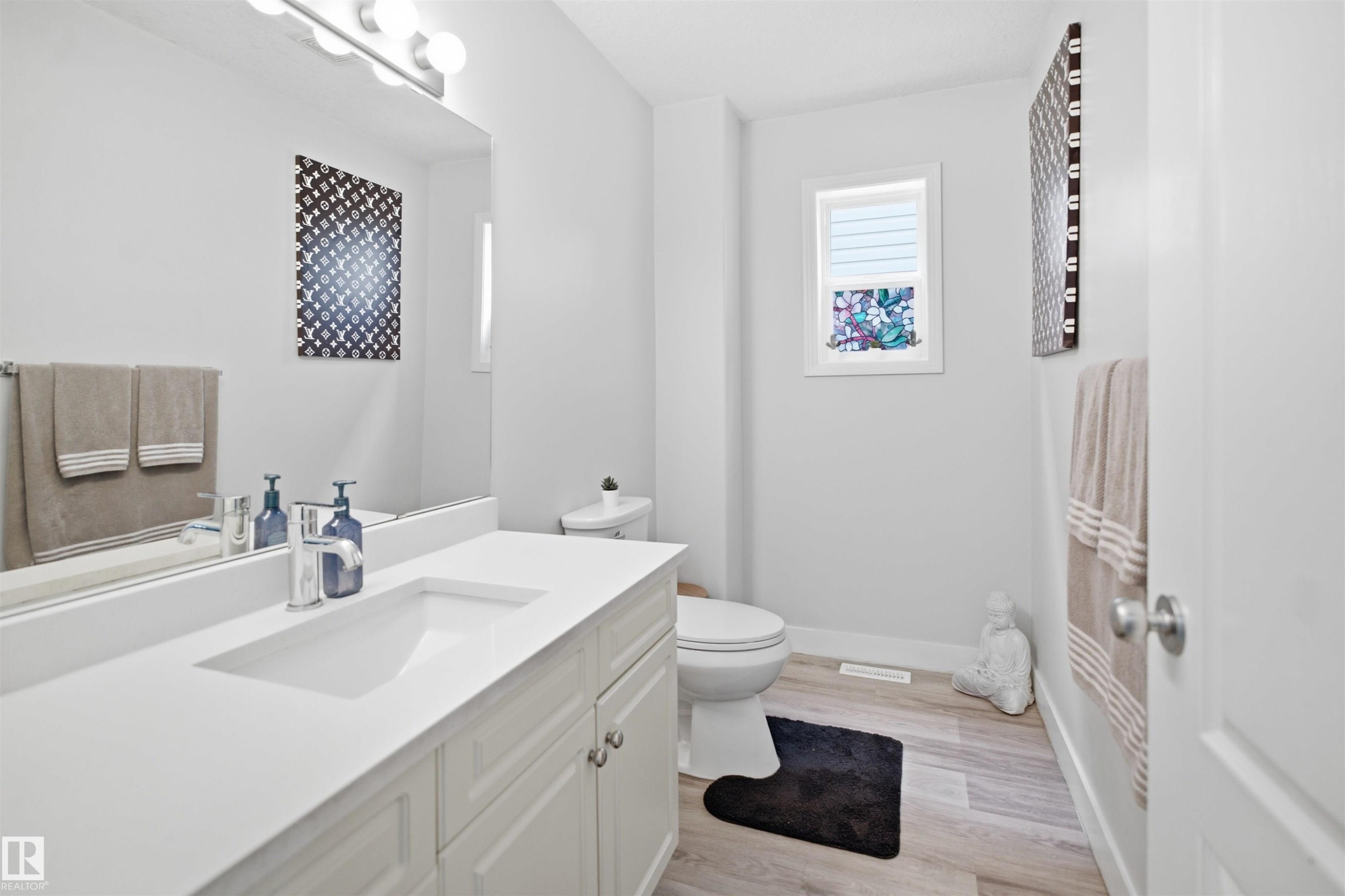 Contemporary bathroom featuring a single vanity with an integrated sink, polished chrome faucet, and white cabinetry - 714 87 Street Sw, Edmonton, AB - Indoor Photo Showing Bathroom