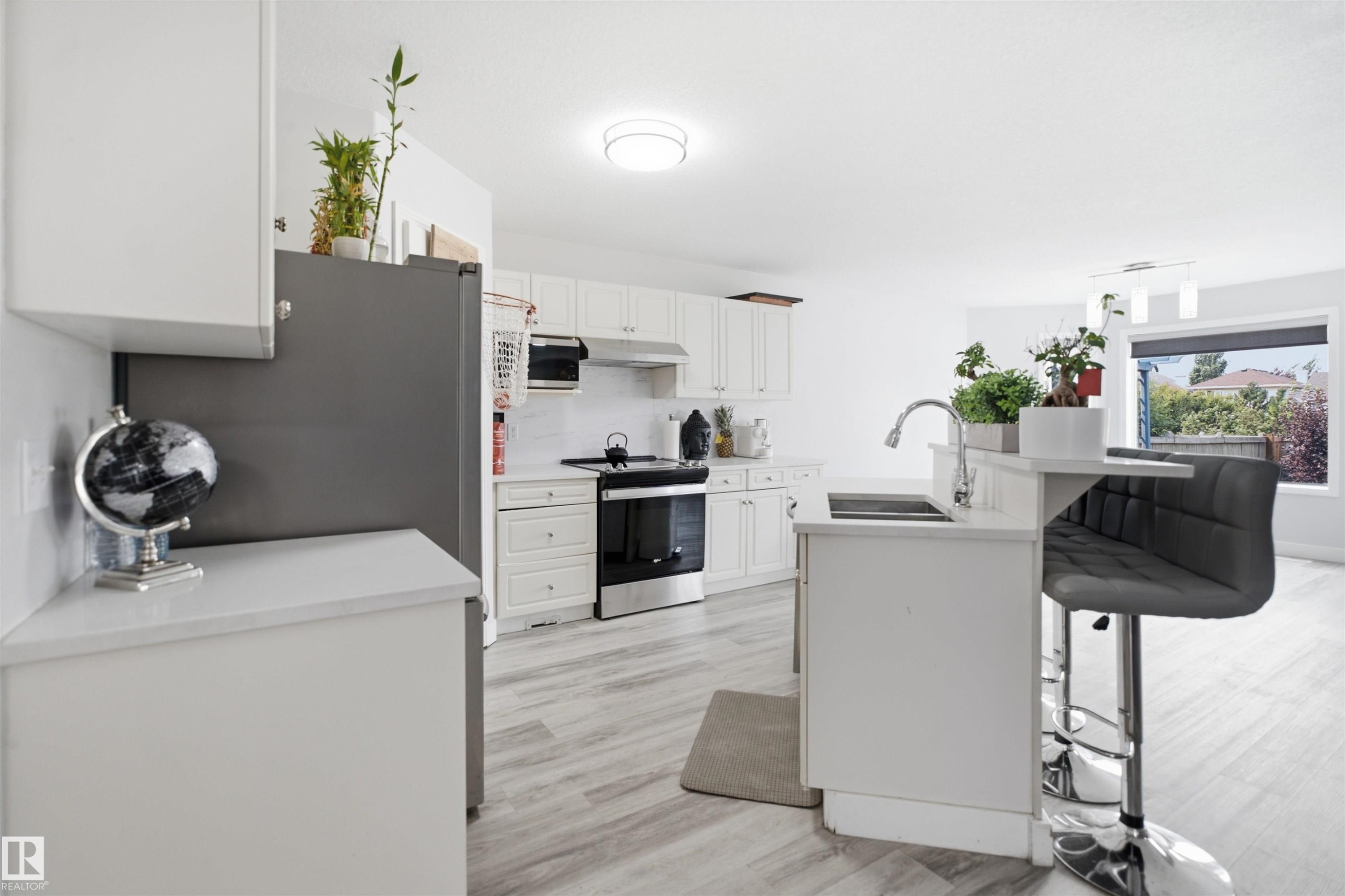Modern kitchen featuring light-toned wood-finish flooring and white cabinetry - 714 87 Street Sw, Edmonton, AB - Indoor Photo Showing Kitchen