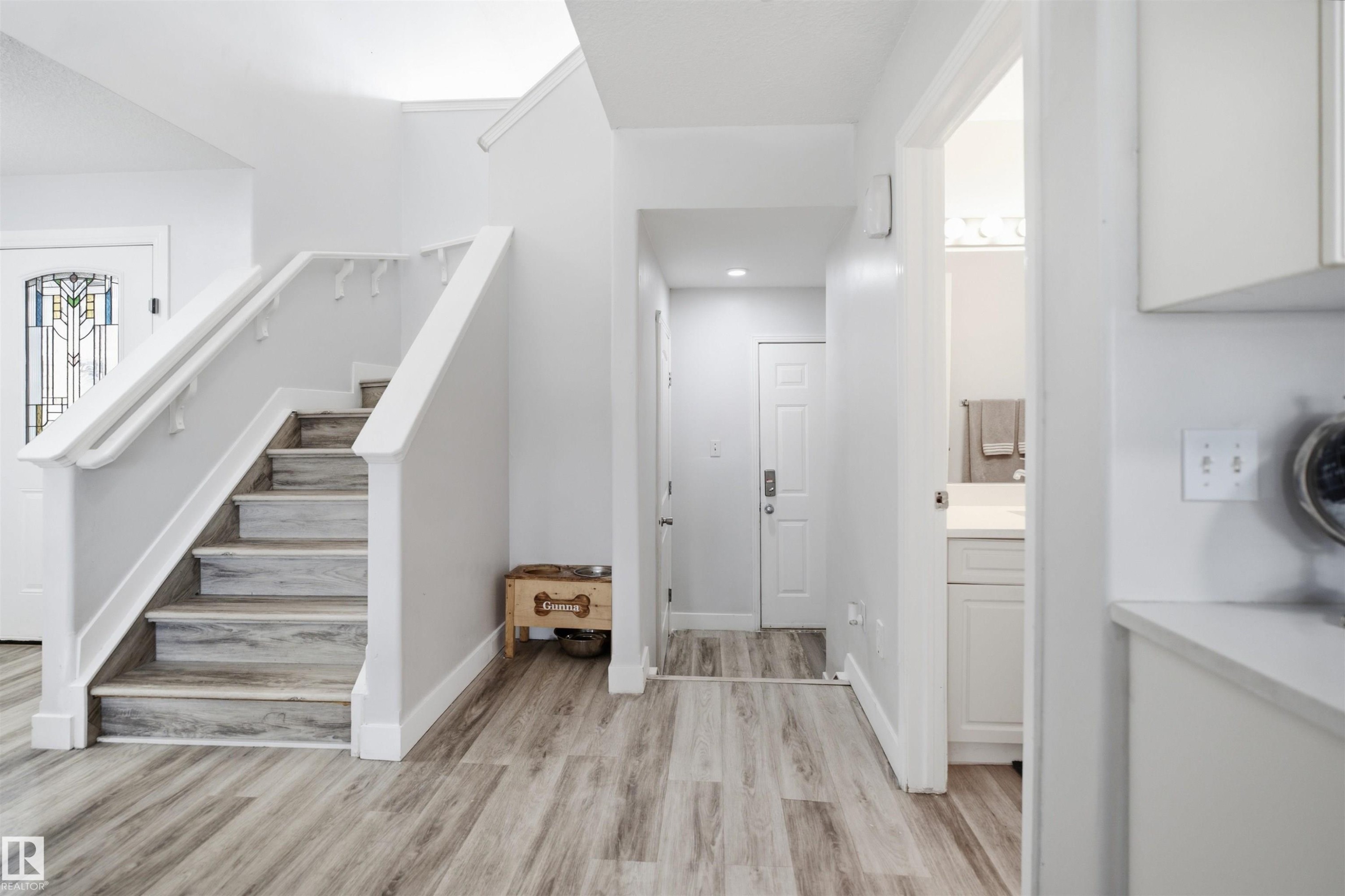 Two-story entryway featuring wood-finish flooring and a white staircase with matching handrails - 714 87 Street Sw, Edmonton, AB - Indoor Photo Showing Other Room