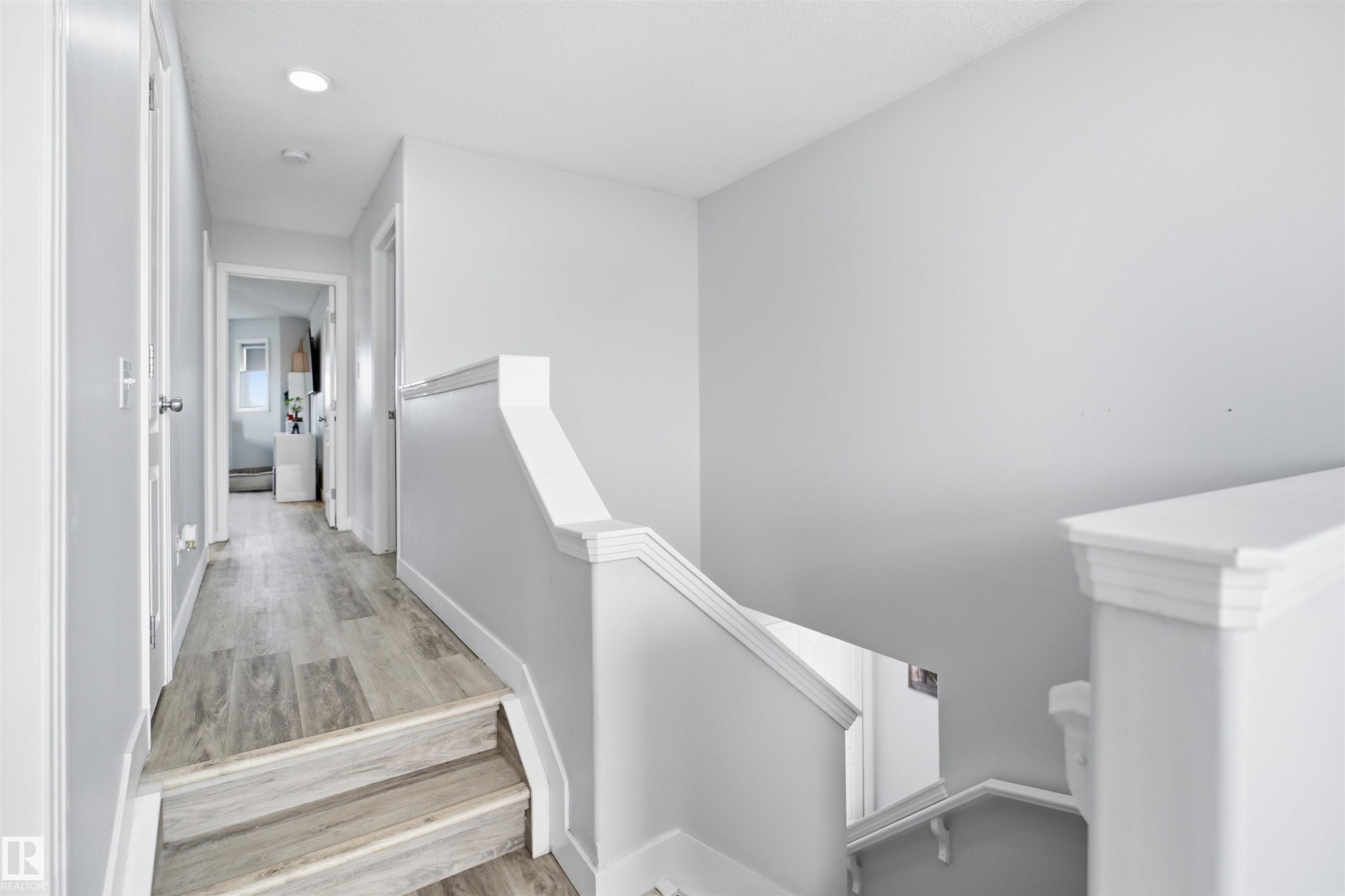 Upper-level hallway featuring light wood-finish flooring, recessed lighting, white baseboards, and a white staircase with a matching handrail - 714 87 Street Sw, Edmonton, AB - Indoor Photo Showing Other Room