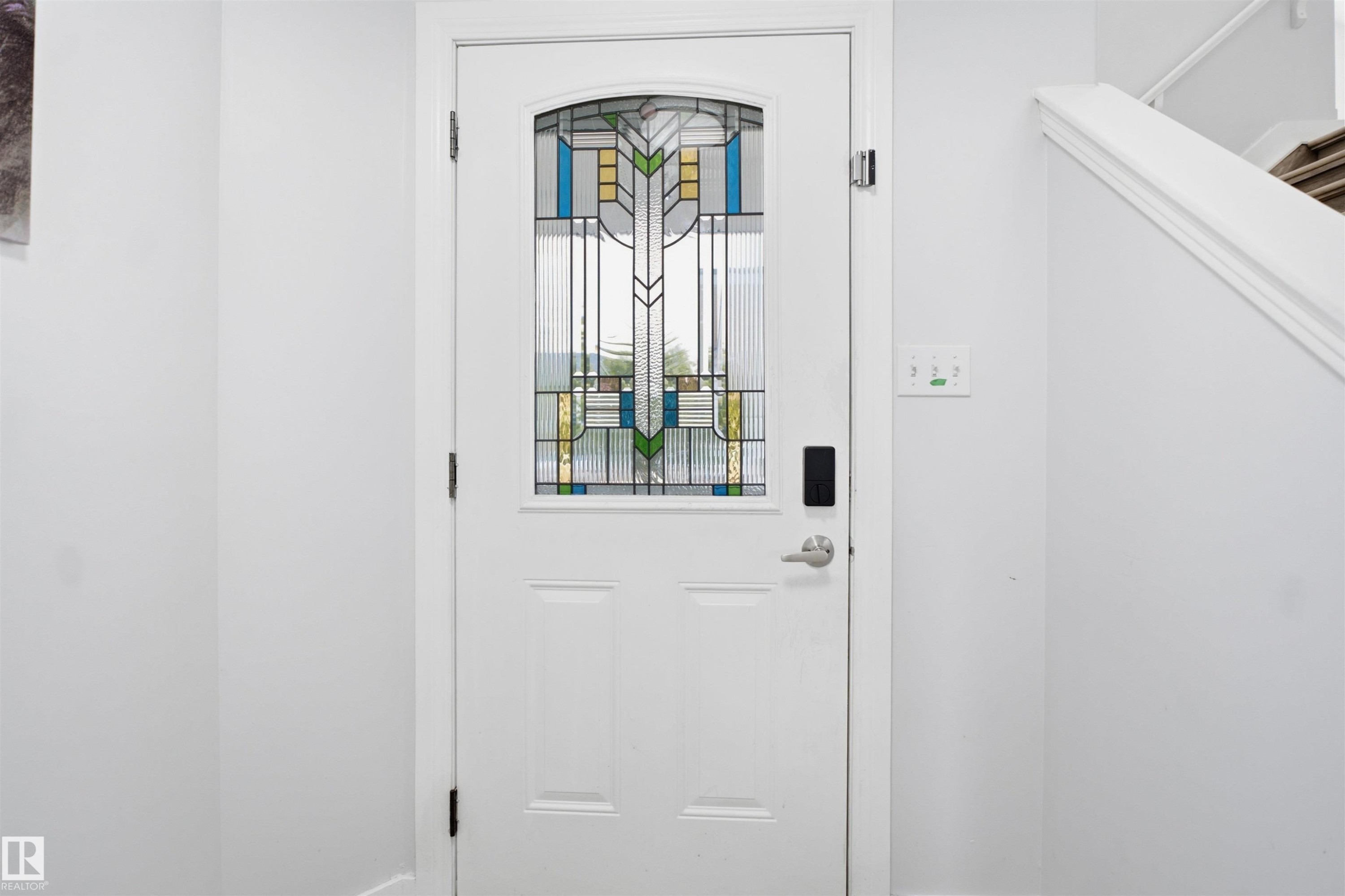 White entry door featuring an arched stained glass insert, a smart lock system, and brushed nickel hardware - 714 87 Street Sw, Edmonton, AB - Indoor Photo Showing Other Room