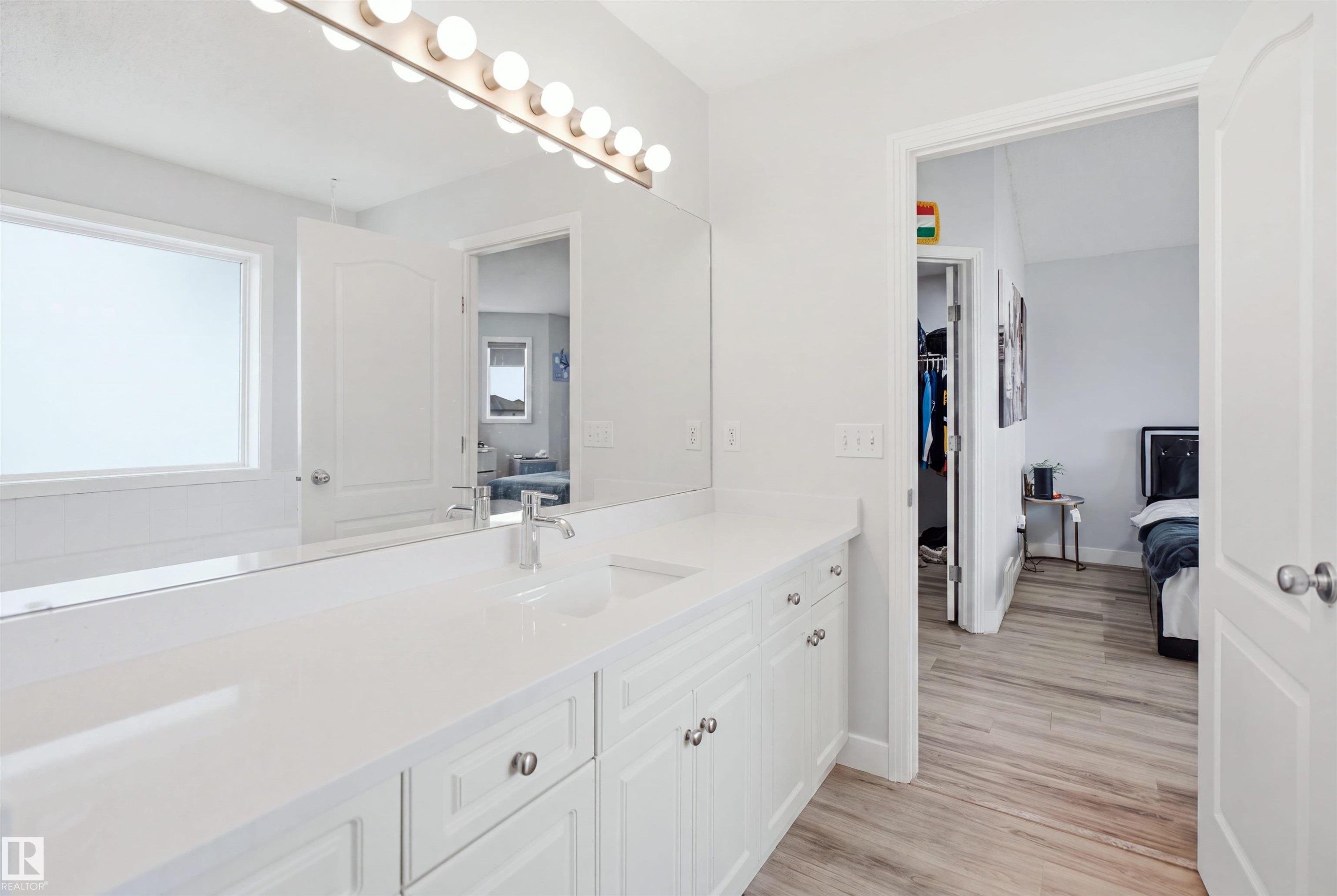 Bright bathroom featuring an extended white vanity with integrated sink, contemporary chrome faucet, and a full-width mirror - 714 87 Street Sw, Edmonton, AB - Indoor Photo Showing Bathroom