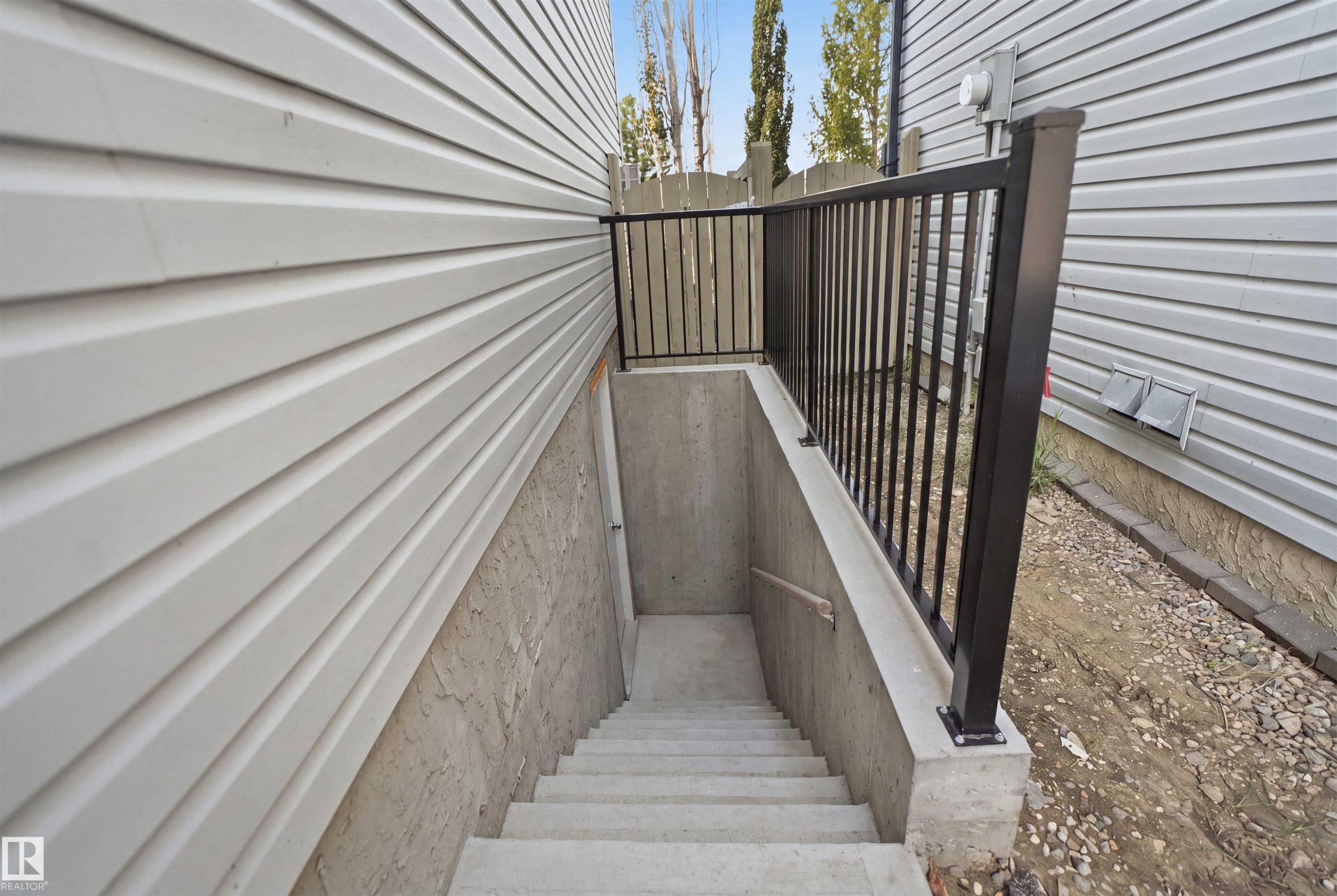 Concrete staircase leading to a lower level entrance, bordered by a black metal railing - 714 87 Street Sw, Edmonton, AB - Outdoor With Exterior