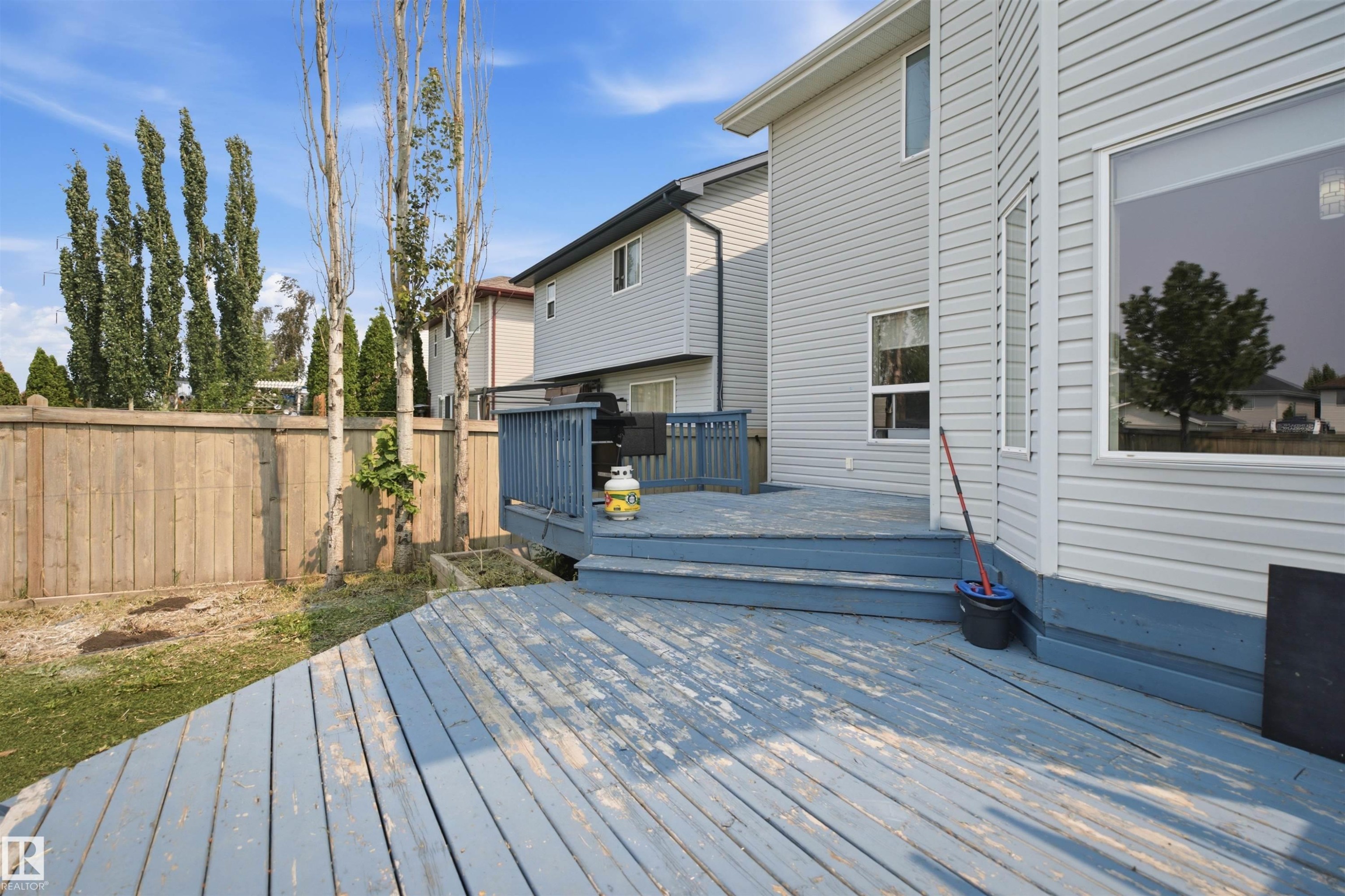 Expansive outdoor deck with integrated steps, leading to a fenced backyard featuring mature trees - 714 87 Street Sw, Edmonton, AB - Outdoor With Deck Patio Veranda
