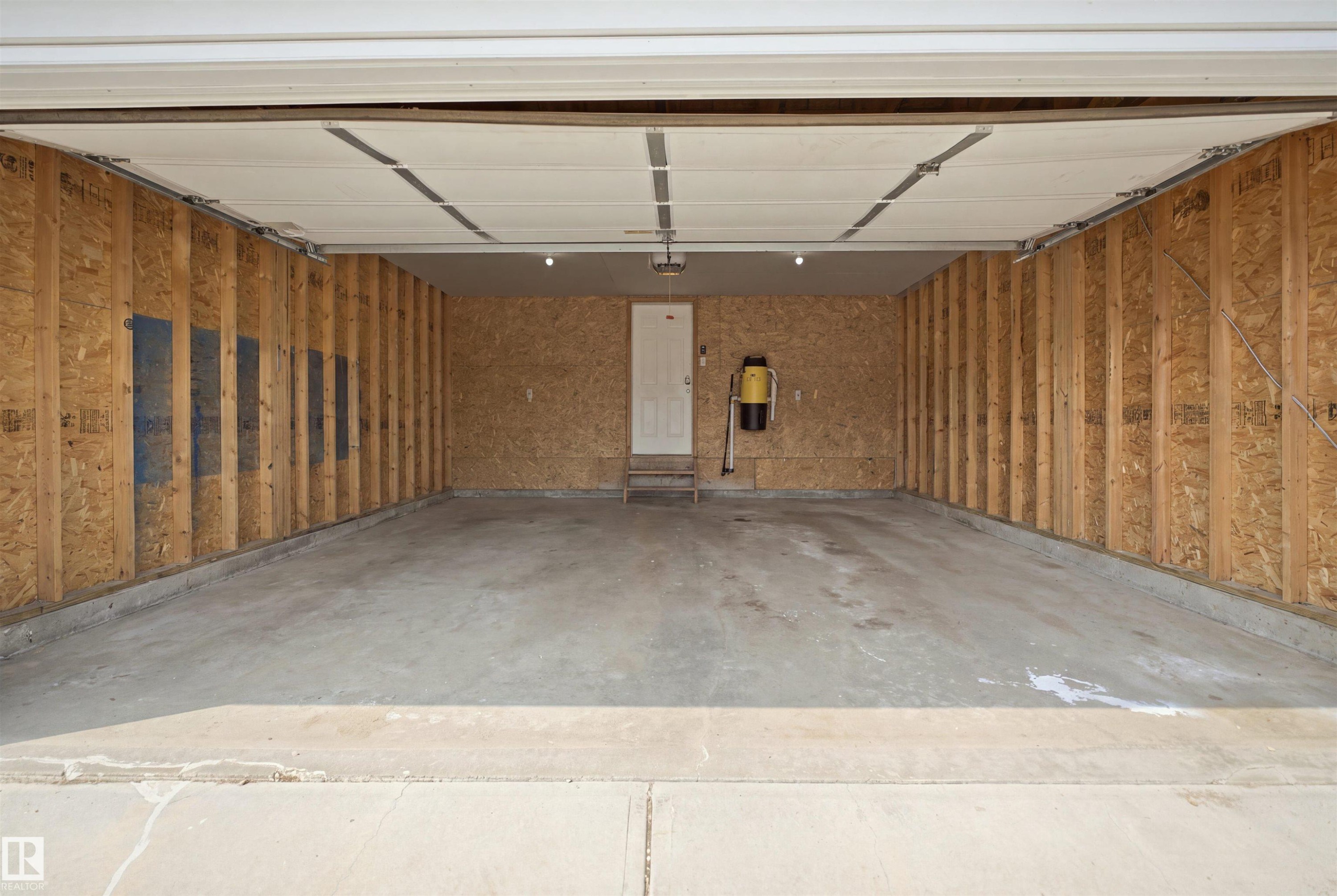 Spacious two-car garage featuring a concrete floor, framed walls, and an overhead door - 714 87 Street Sw, Edmonton, AB - Indoor Photo Showing Garage