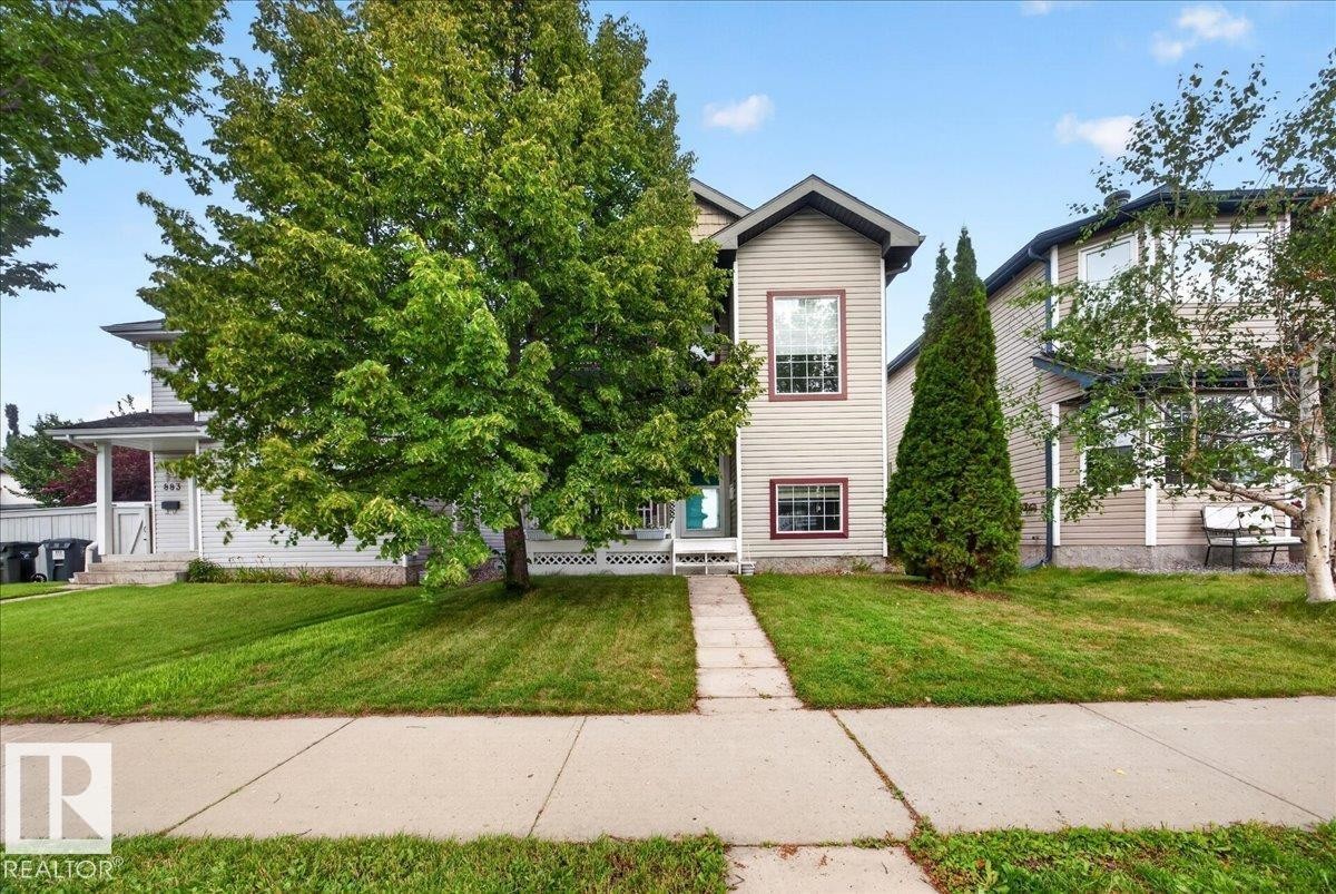 Two-story residence featuring neutral siding exterior, symmetrical facade with multi-pane windows, and a welcoming front entrance - 887 Oakland Boulevard, Devon, AB - Outdoor