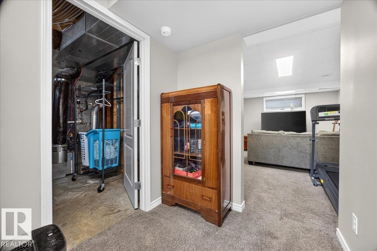 Utility room featuring organized storage with white-framed door, wood-finish cabinet with glass panels, concrete flooring, and access to mechanical systems - 887 Oakland Boulevard, Devon, AB - Indoor