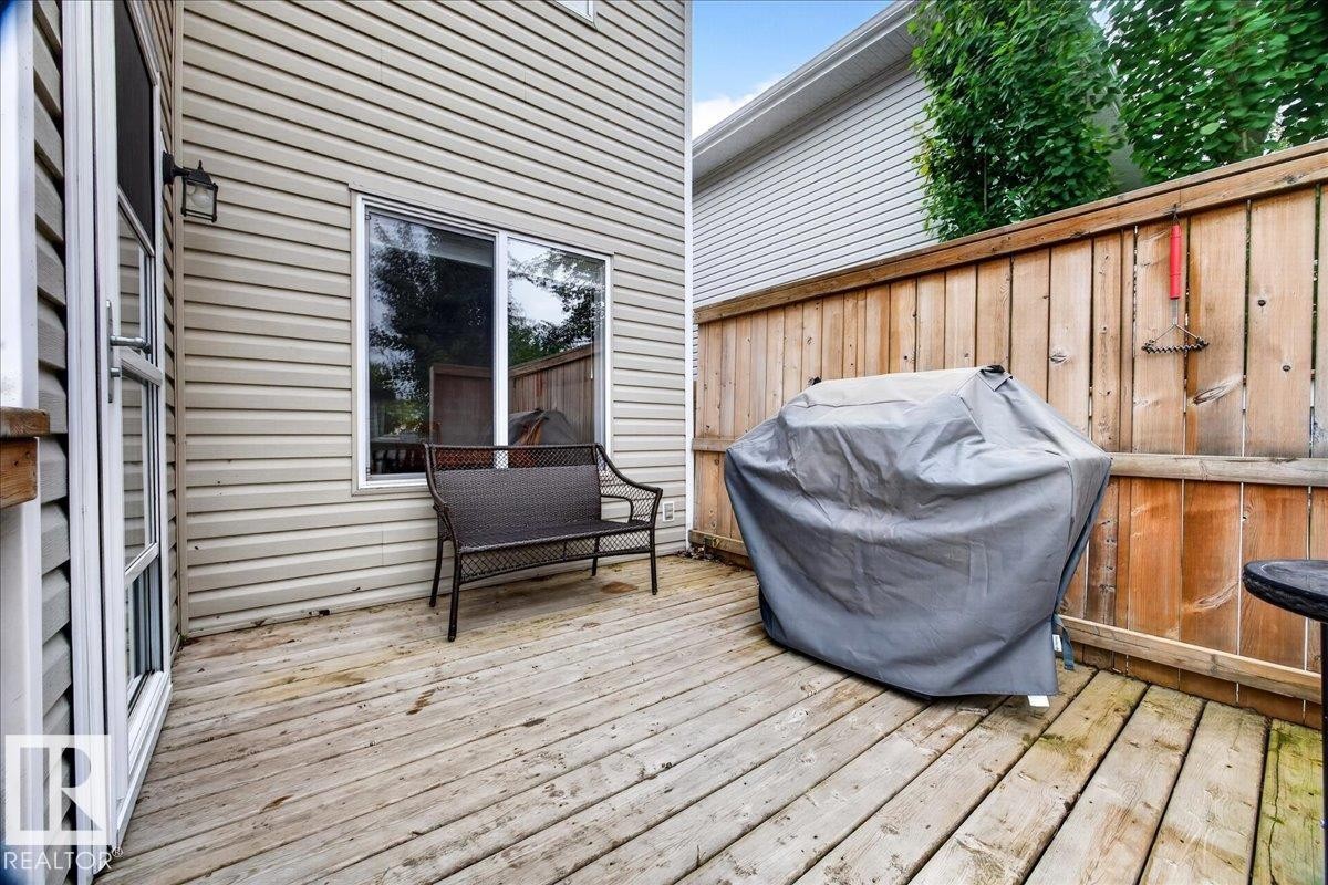 Spacious composite deck featuring horizontal wood-finish decking, accessible glass sliding doors, and wooden privacy fencing - 887 Oakland Boulevard, Devon, AB - Outdoor With Deck Patio Veranda With Exterior