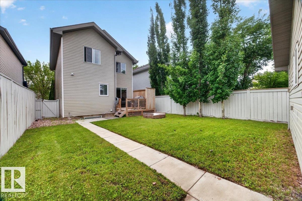 Expansive backyard featuring a manicured lawn, a wooden deck, and mature trees - 887 Oakland Boulevard, Devon, AB - Outdoor
