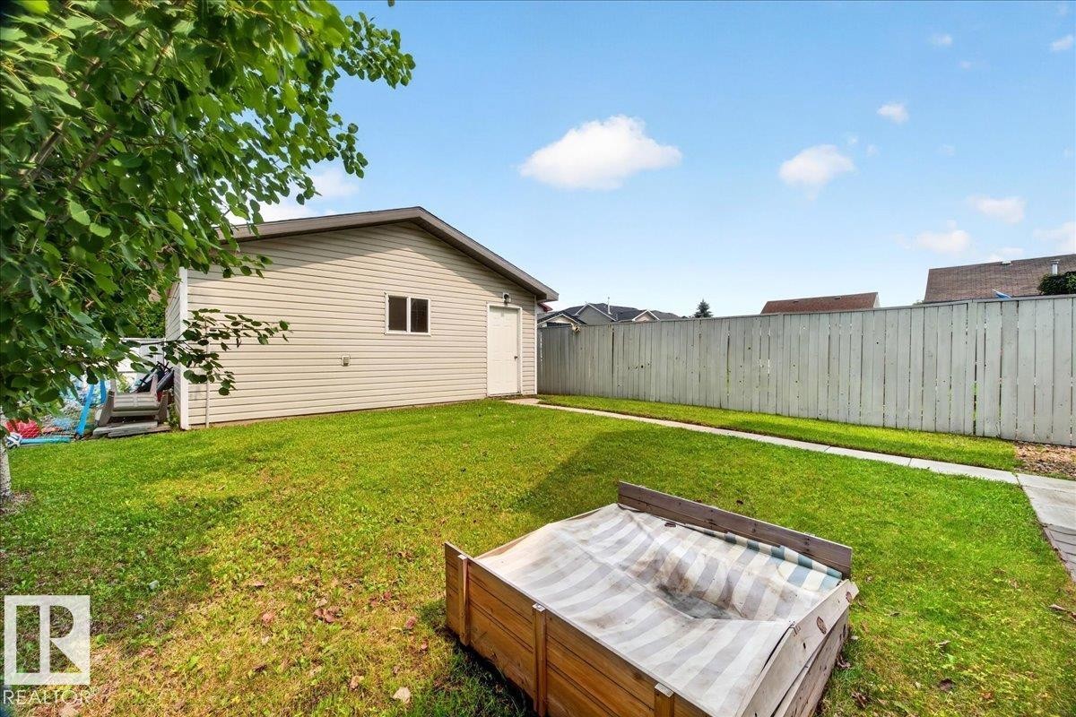 Spacious backyard featuring a mature lawn, wood-finish fencing, and mature landscaping - 887 Oakland Boulevard, Devon, AB - Outdoor