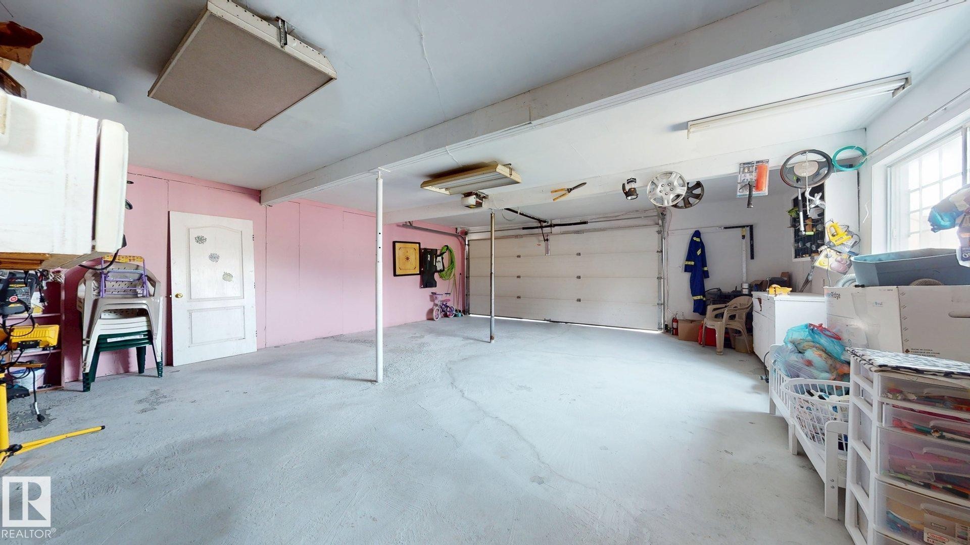 Spacious garage featuring a concrete floor, overhead lighting, an automatic garage door, and a built-in window - 12812 45 Street Nw, Edmonton, AB - Indoor Photo Showing Garage