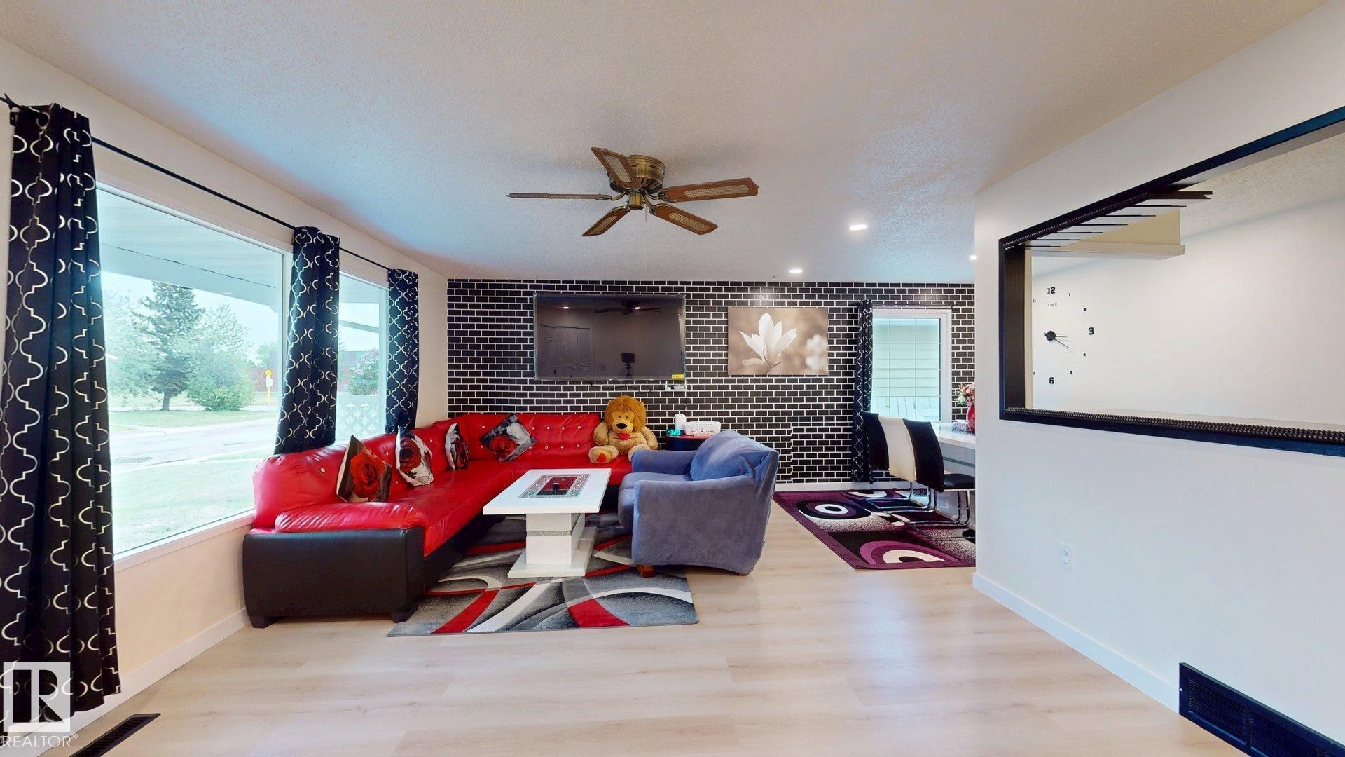 Spacious living area featuring light wood-finish flooring, a contemporary ceiling fan, and recessed lighting - 12812 45 Street Nw, Edmonton, AB - Indoor