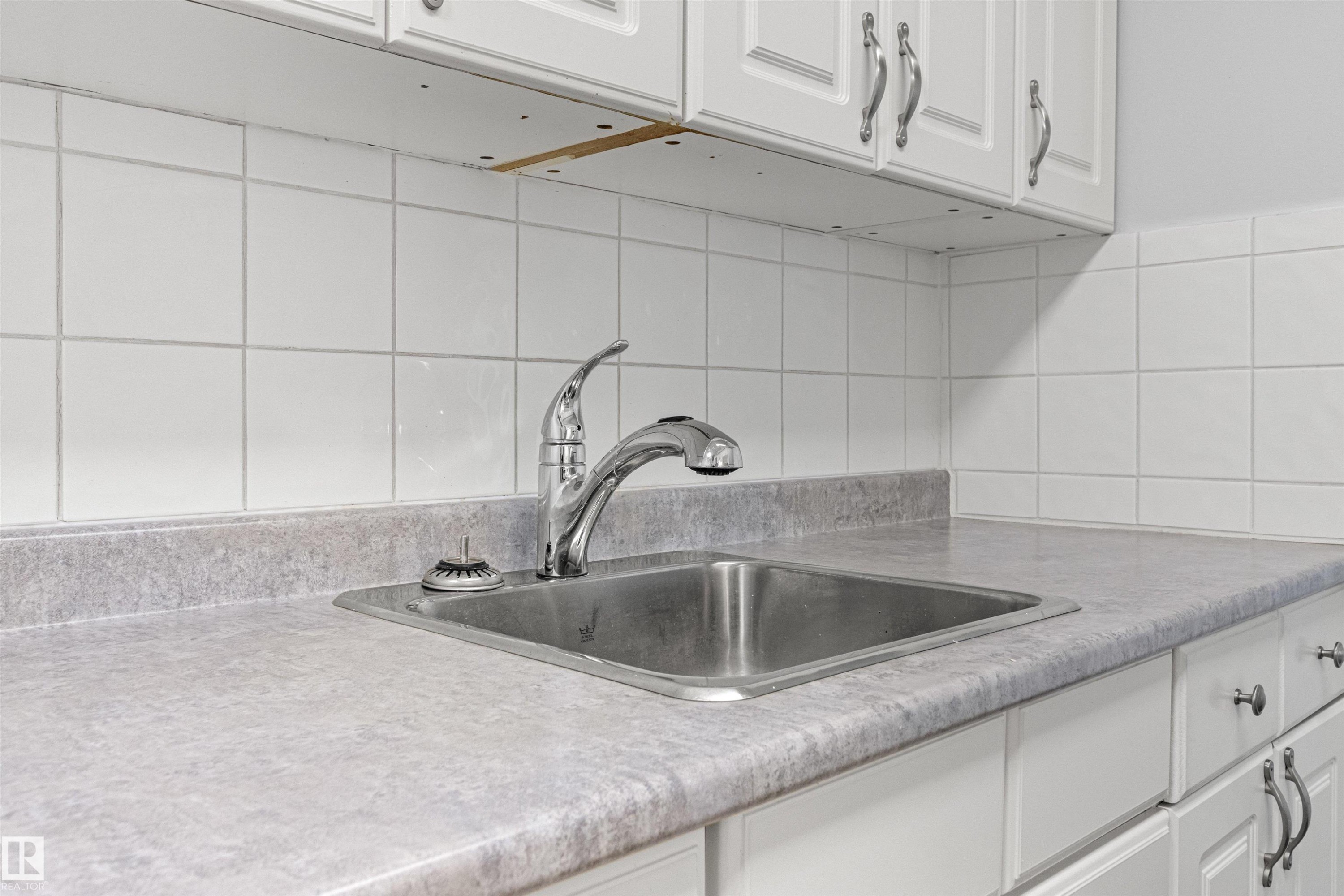 White paneled cabinetry, laminate countertops, stainless steel sink, chrome faucet, and tiled backsplash - #9 14230 80 St Nw, Edmonton, AB - Indoor Photo Showing Kitchen