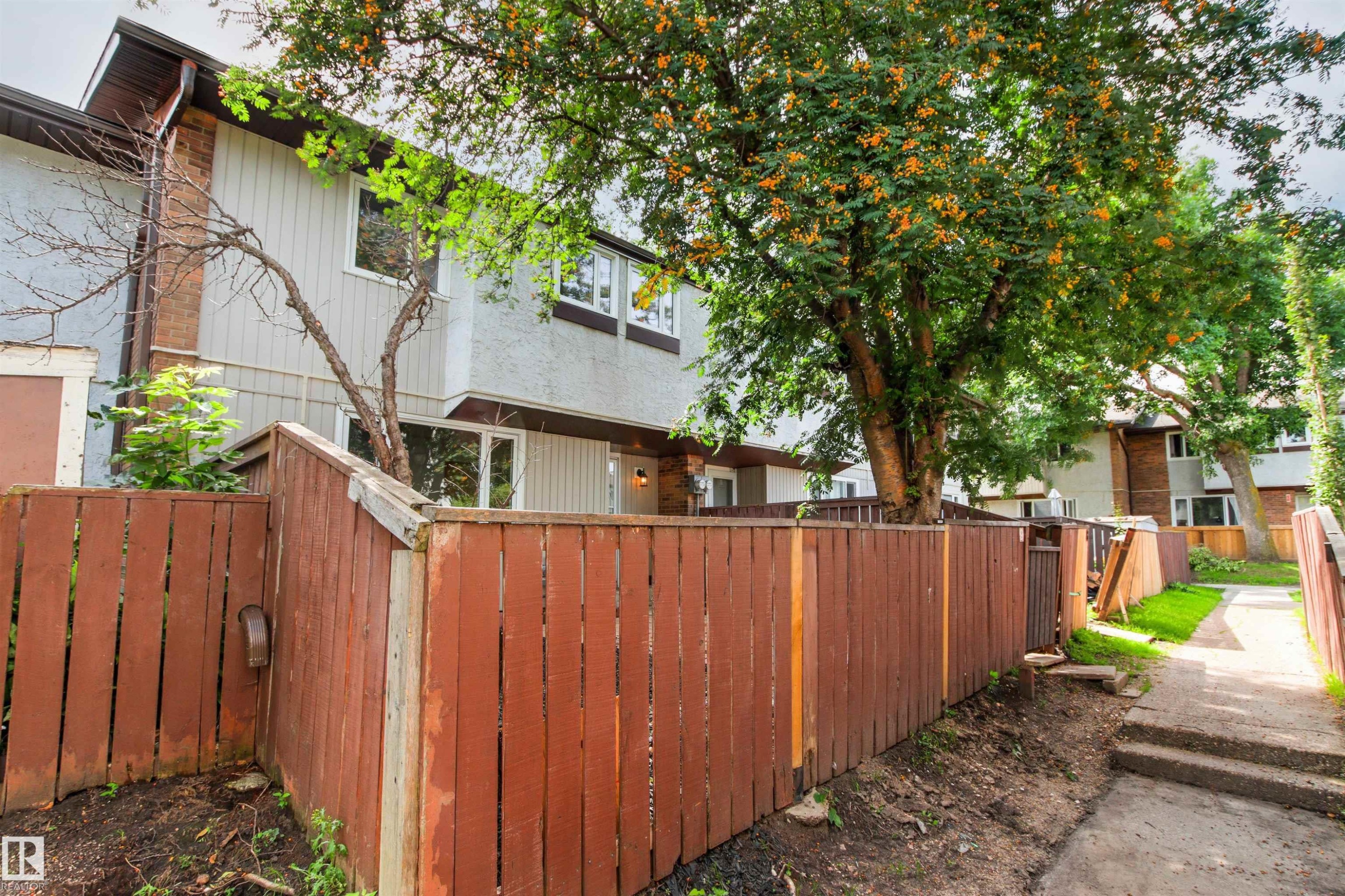Townhome exterior with light-colored siding and a brown roofline - #9 14230 80 St Nw, Edmonton, AB - Outdoor