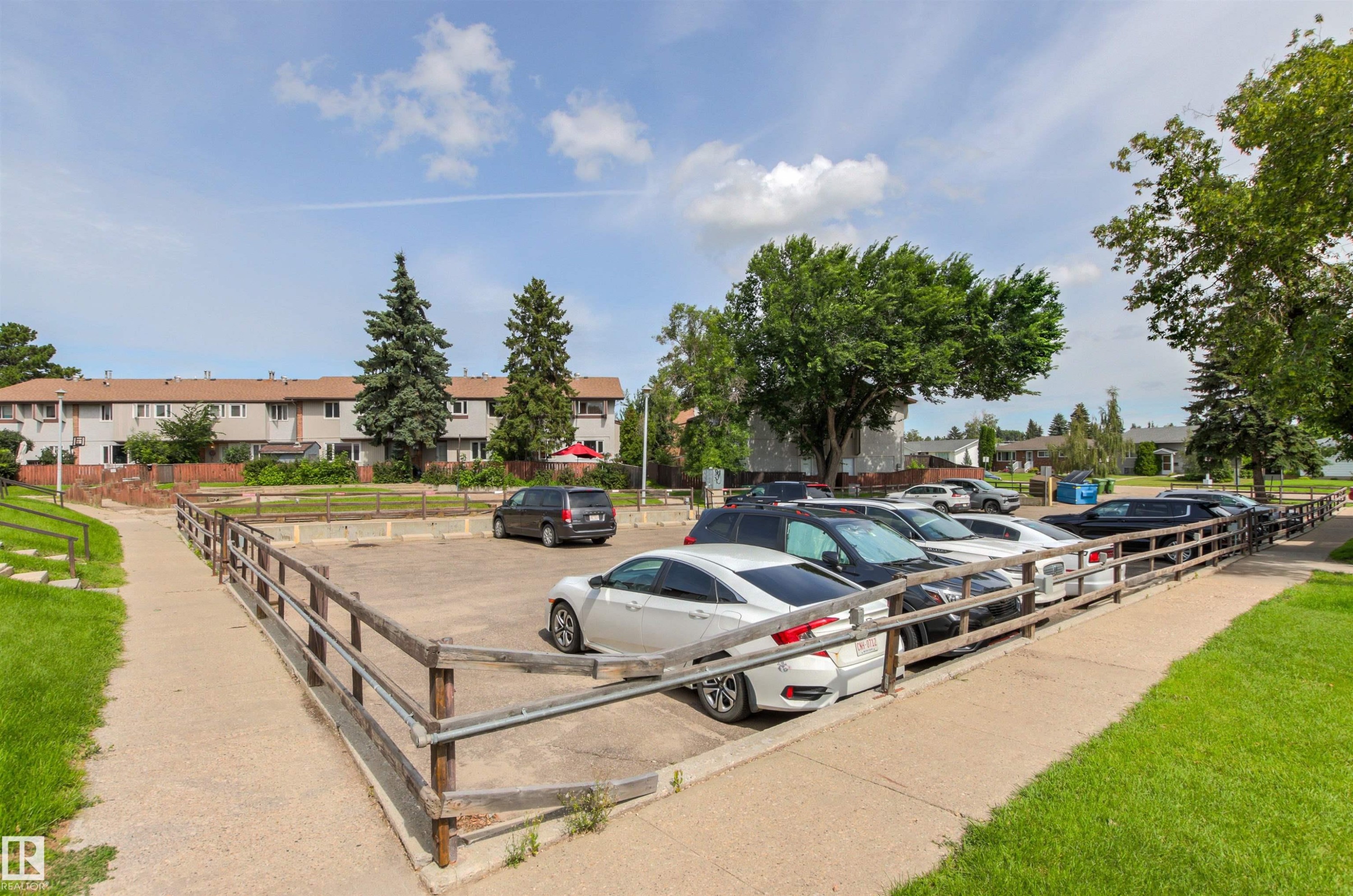 Paved parking area bordered by wooden fencing and a concrete path - #9 14230 80 St Nw, Edmonton, AB - Outdoor
