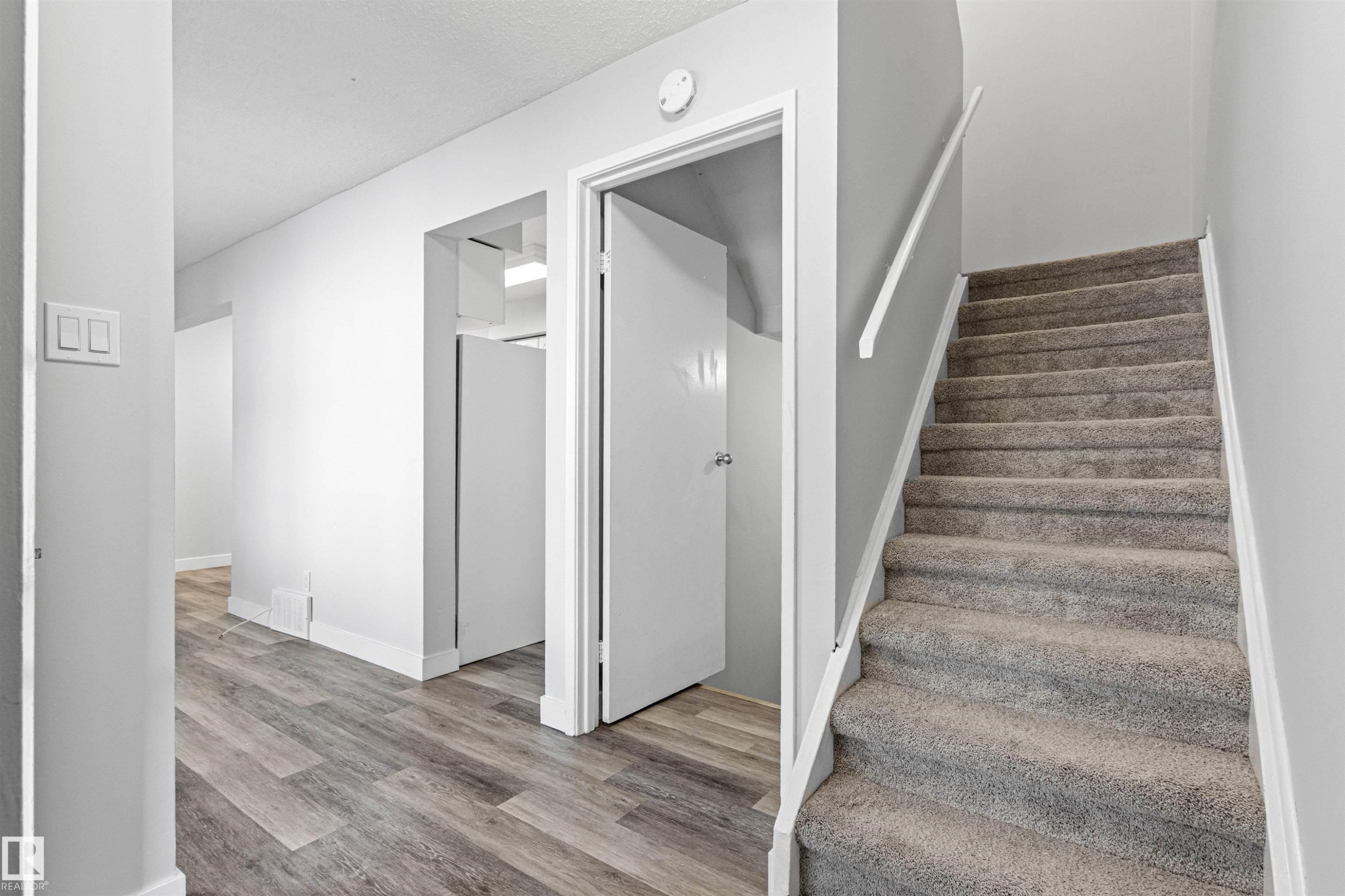 Wood-finish flooring, light grey carpeting, white trim throughout, and a white handrail - #9 14230 80 St Nw, Edmonton, AB - Indoor Photo Showing Other Room
