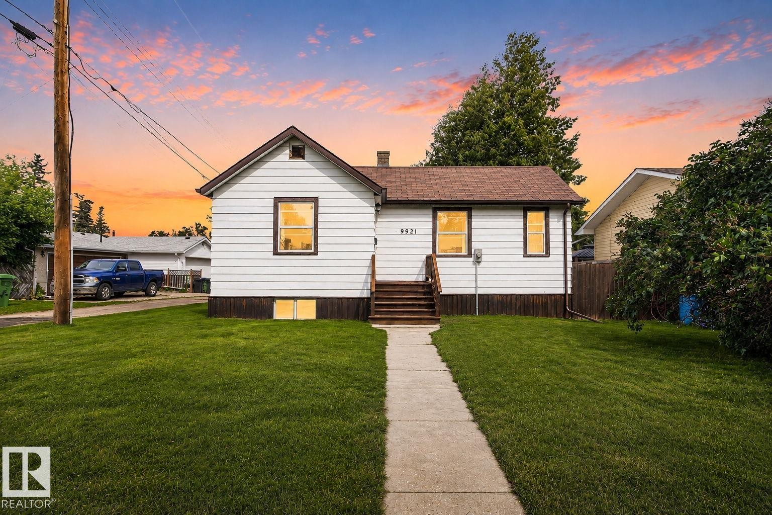 White siding exterior with a brown shingle roof, dark trim, and a concrete pathway - 9921 109 Street, Fort Saskatchewan, AB - Outdoor