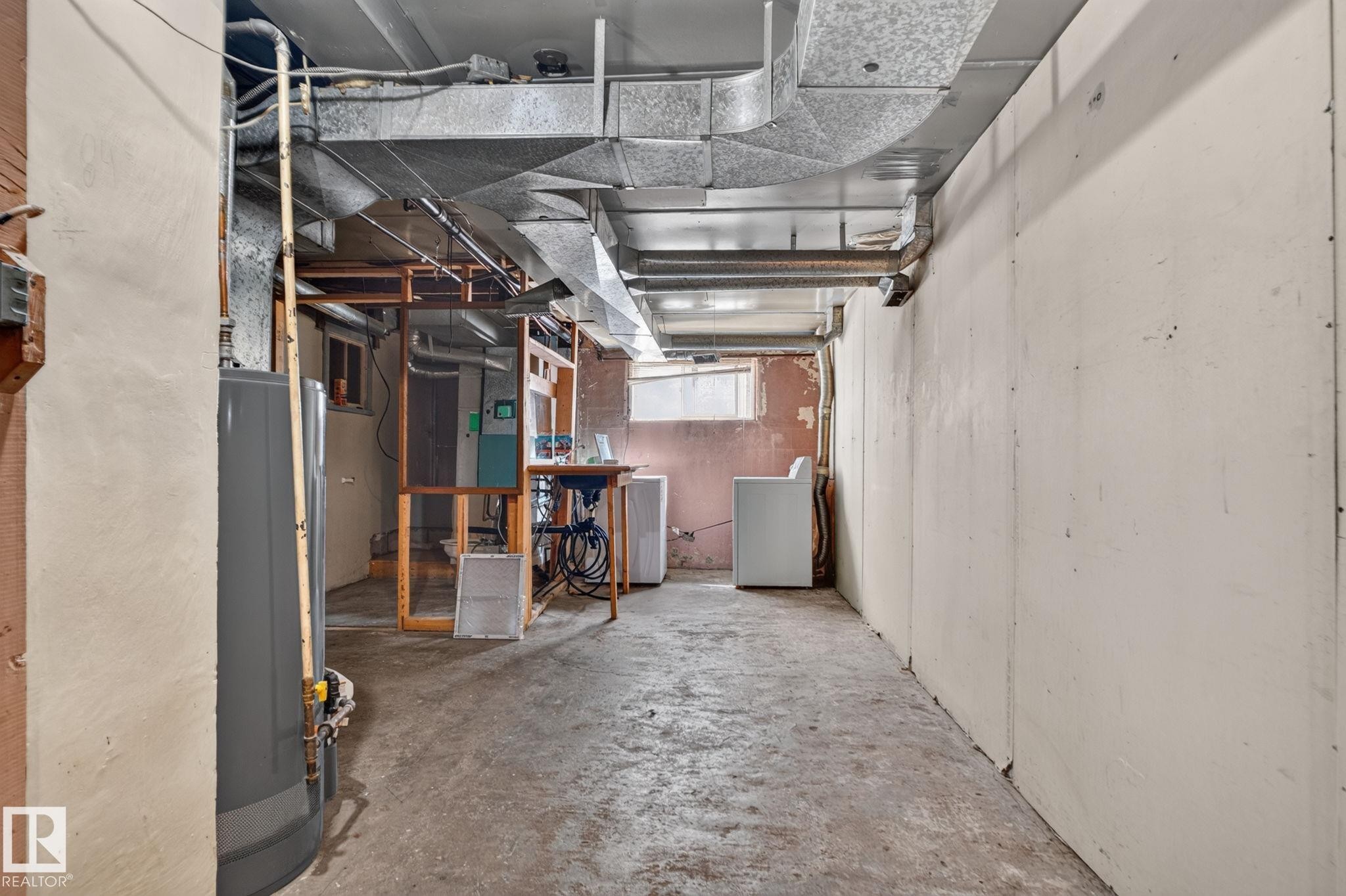 Unfinished basement with concrete flooring, exposed ductwork, and a utility sink - 9921 109 Street, Fort Saskatchewan, AB - Indoor Photo Showing Basement