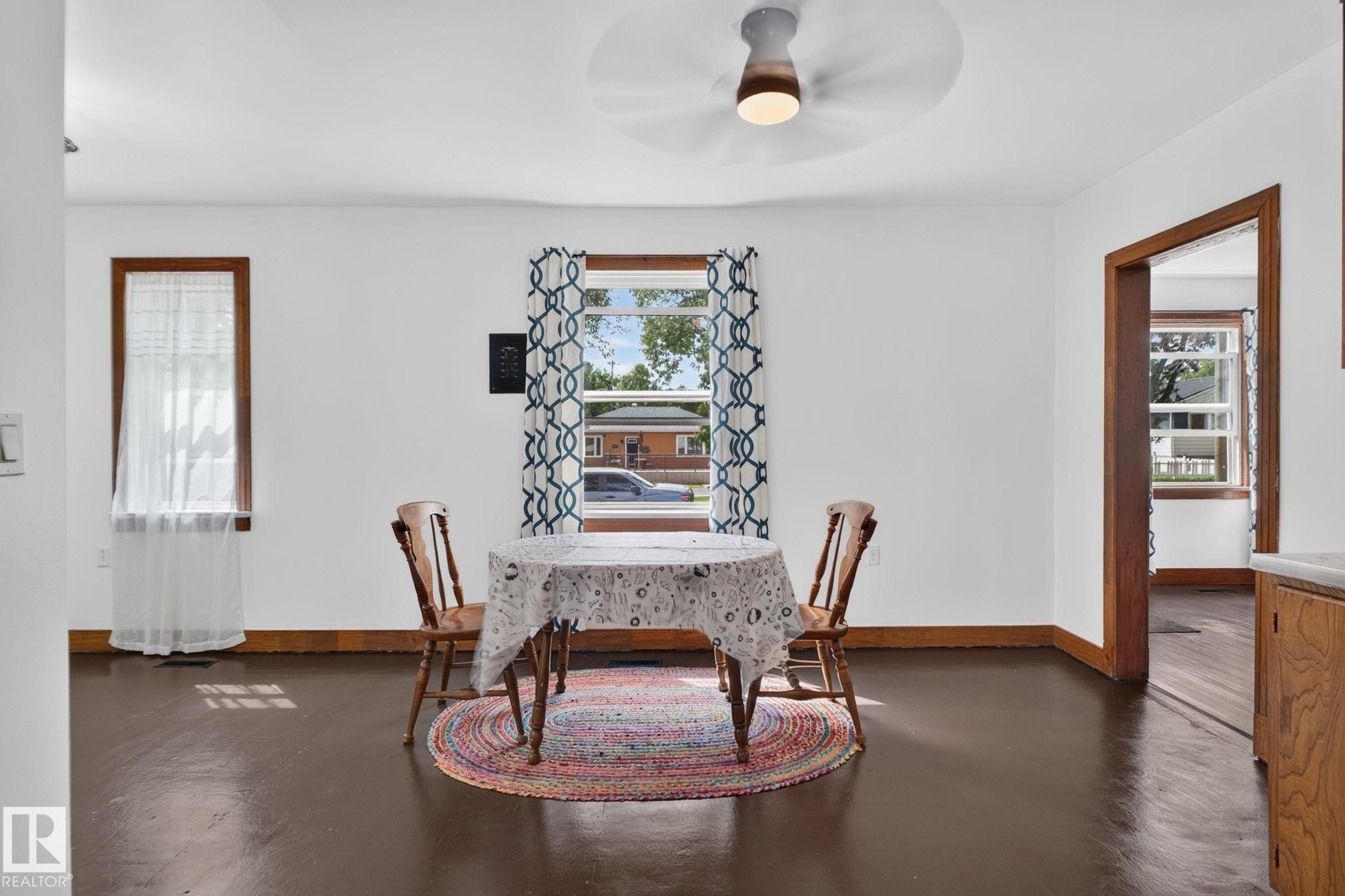 Bright interior with white walls, dark wood-finish flooring, and natural wood trim around windows and doorways - 9921 109 Street, Fort Saskatchewan, AB - Indoor Photo Showing Dining Room
