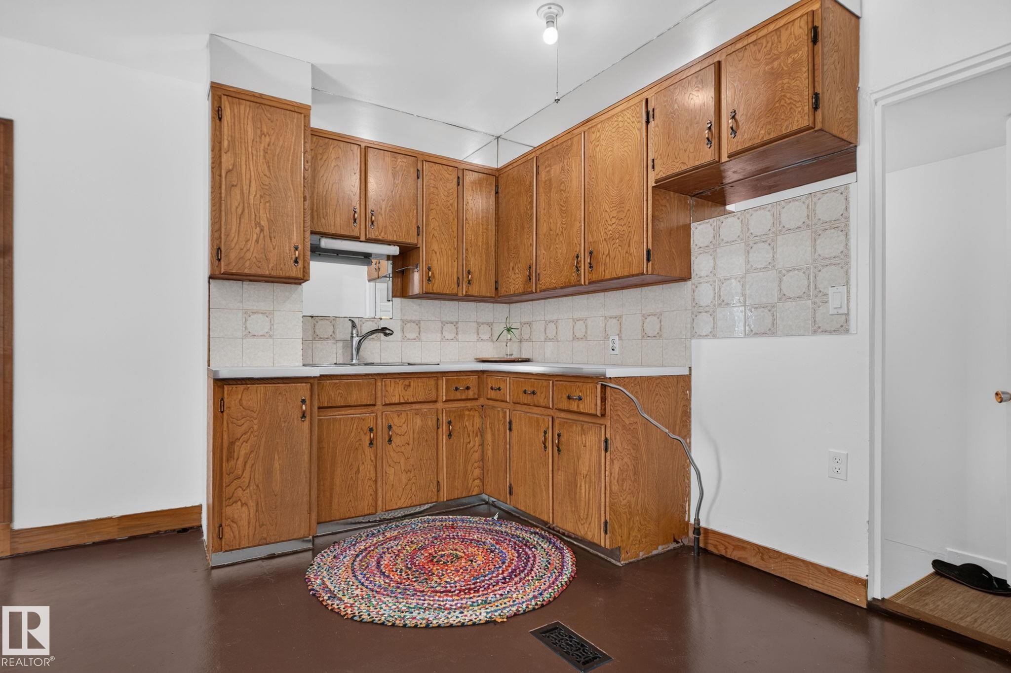 Wood cabinetry with ample storage, white countertops, and a patterned tile backsplash - 9921 109 Street, Fort Saskatchewan, AB - Indoor Photo Showing Kitchen
